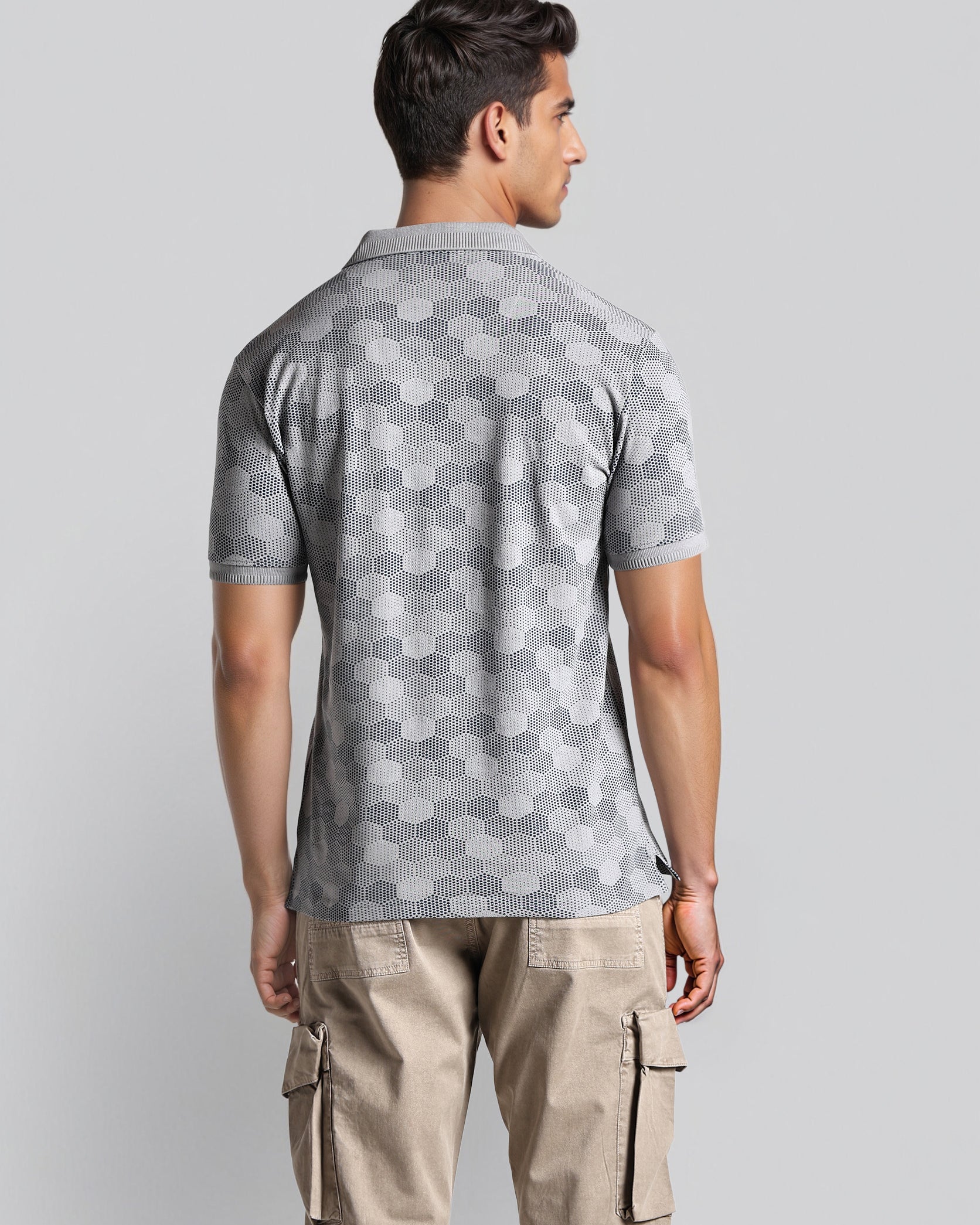 Man wearing a gray patterned polo shirt and beige cargo pants on a light gray background