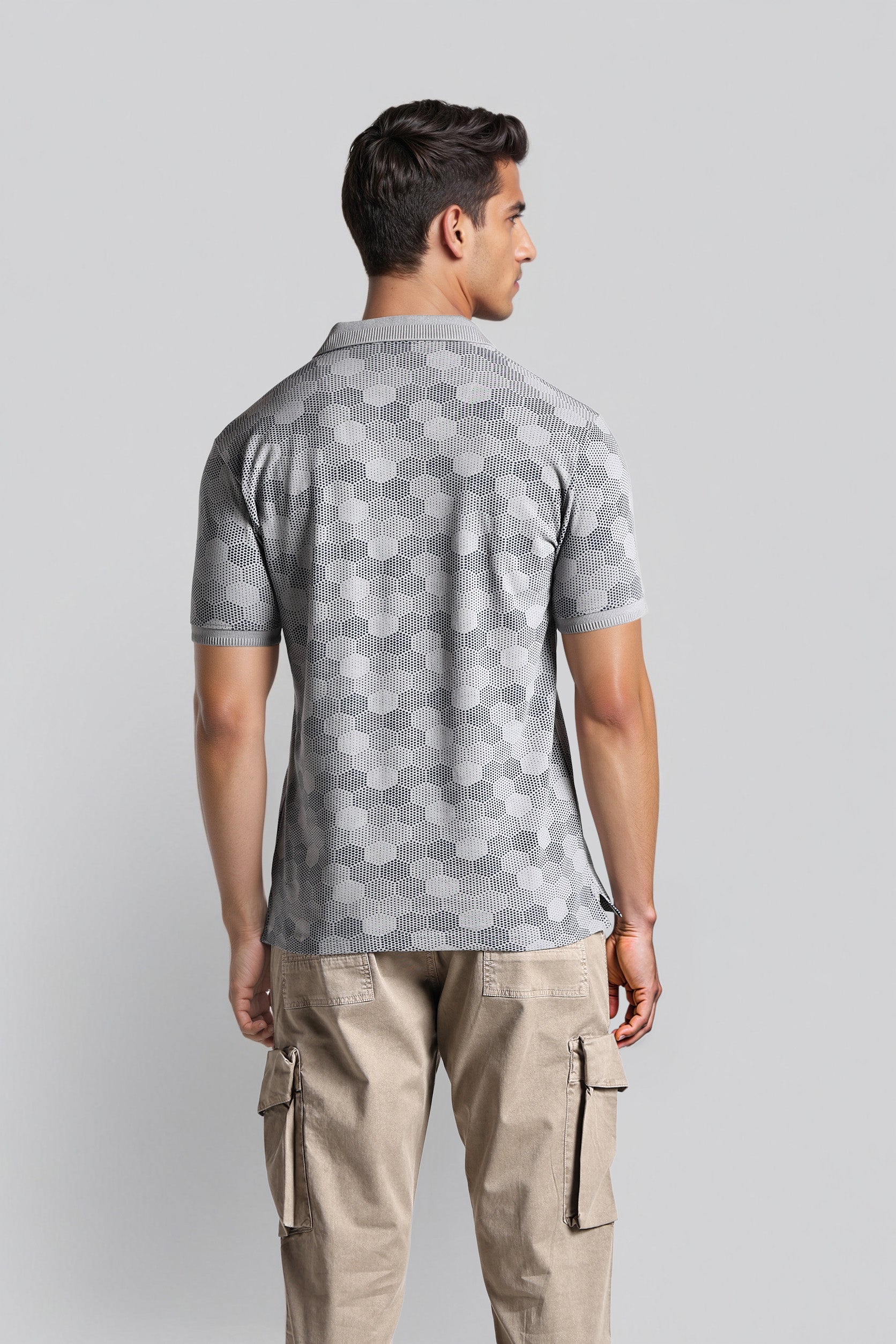 Man wearing a gray patterned polo shirt and beige cargo pants on a light gray background