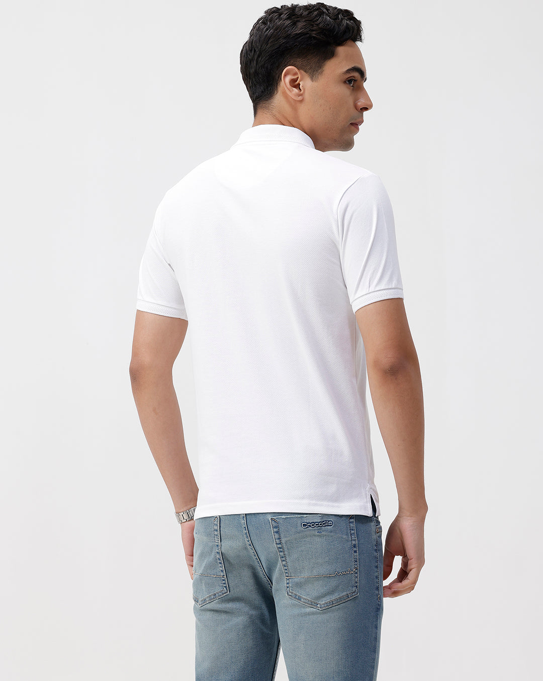 Man wearing a white solid white slim fit polo t shirt with casual styling on a gray background