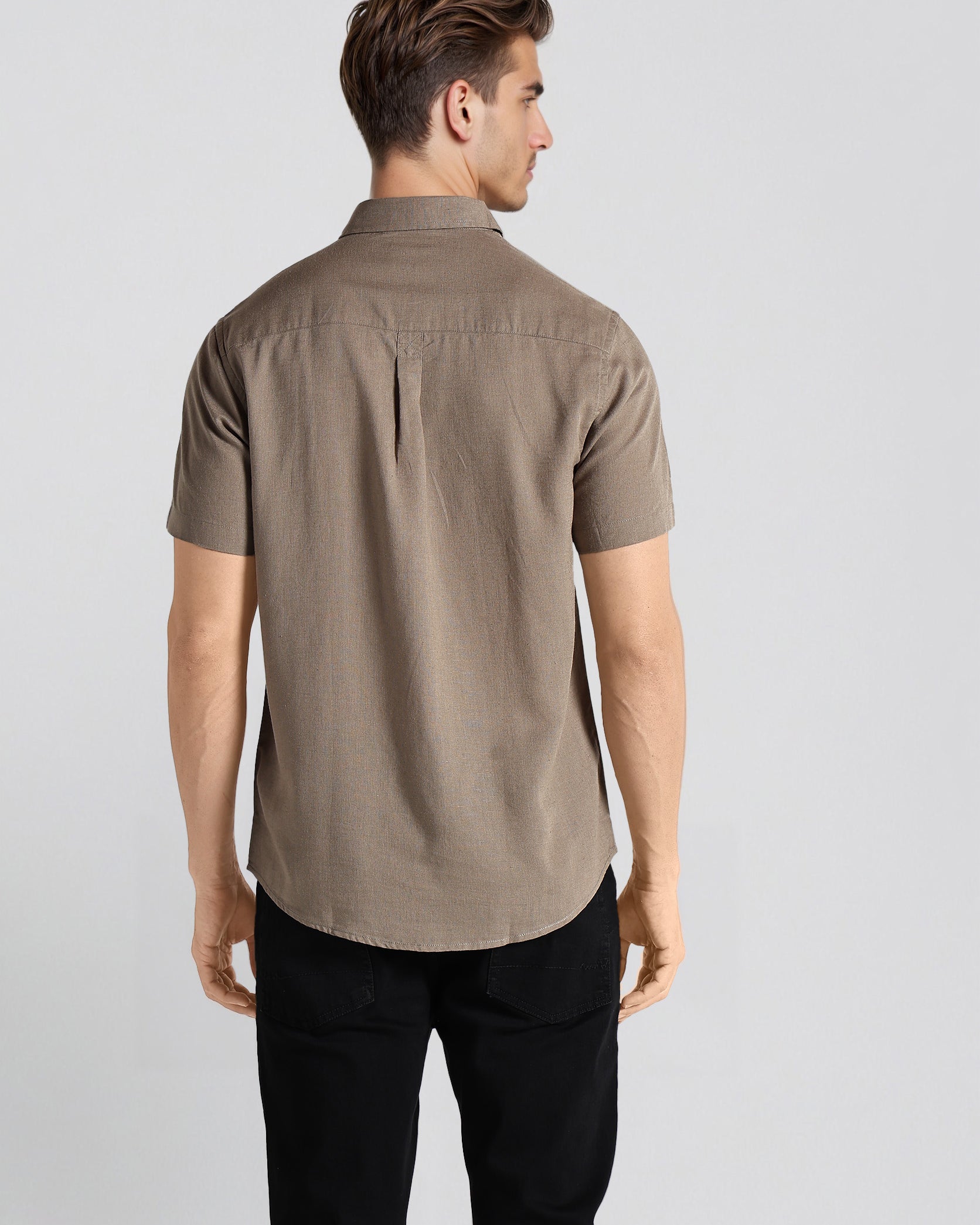 Man wearing a brown shirt and black pants on a white background