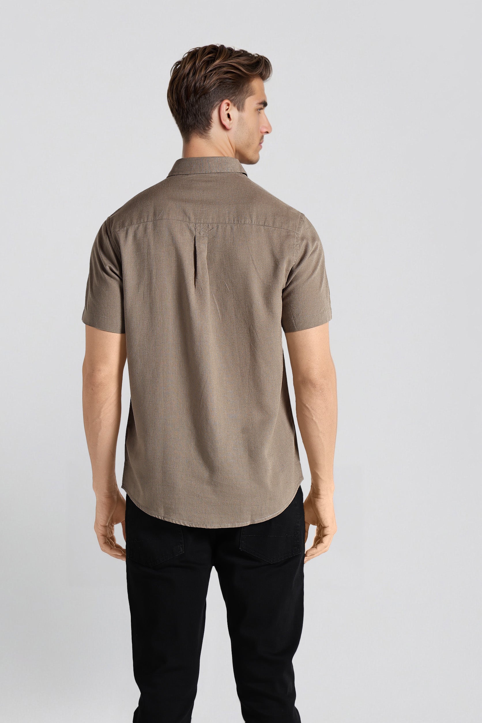 Man wearing a brown shirt and black pants on a white background