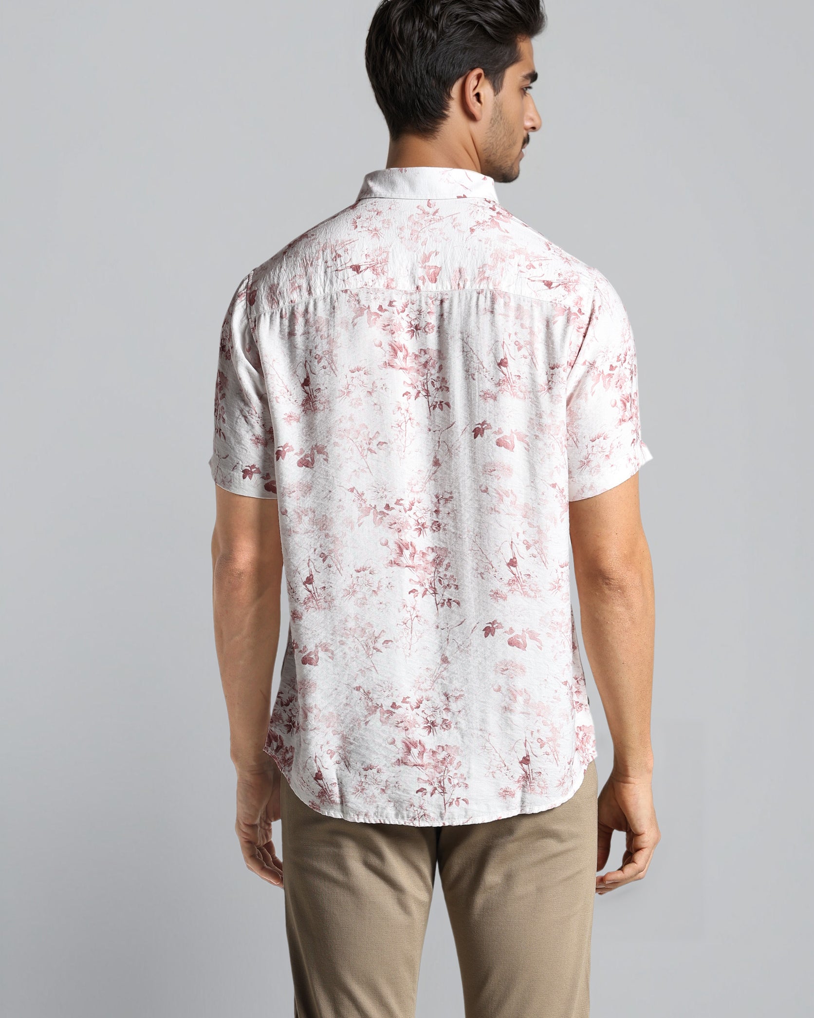 Man wearing a white floral patterned shirt against a gray background
