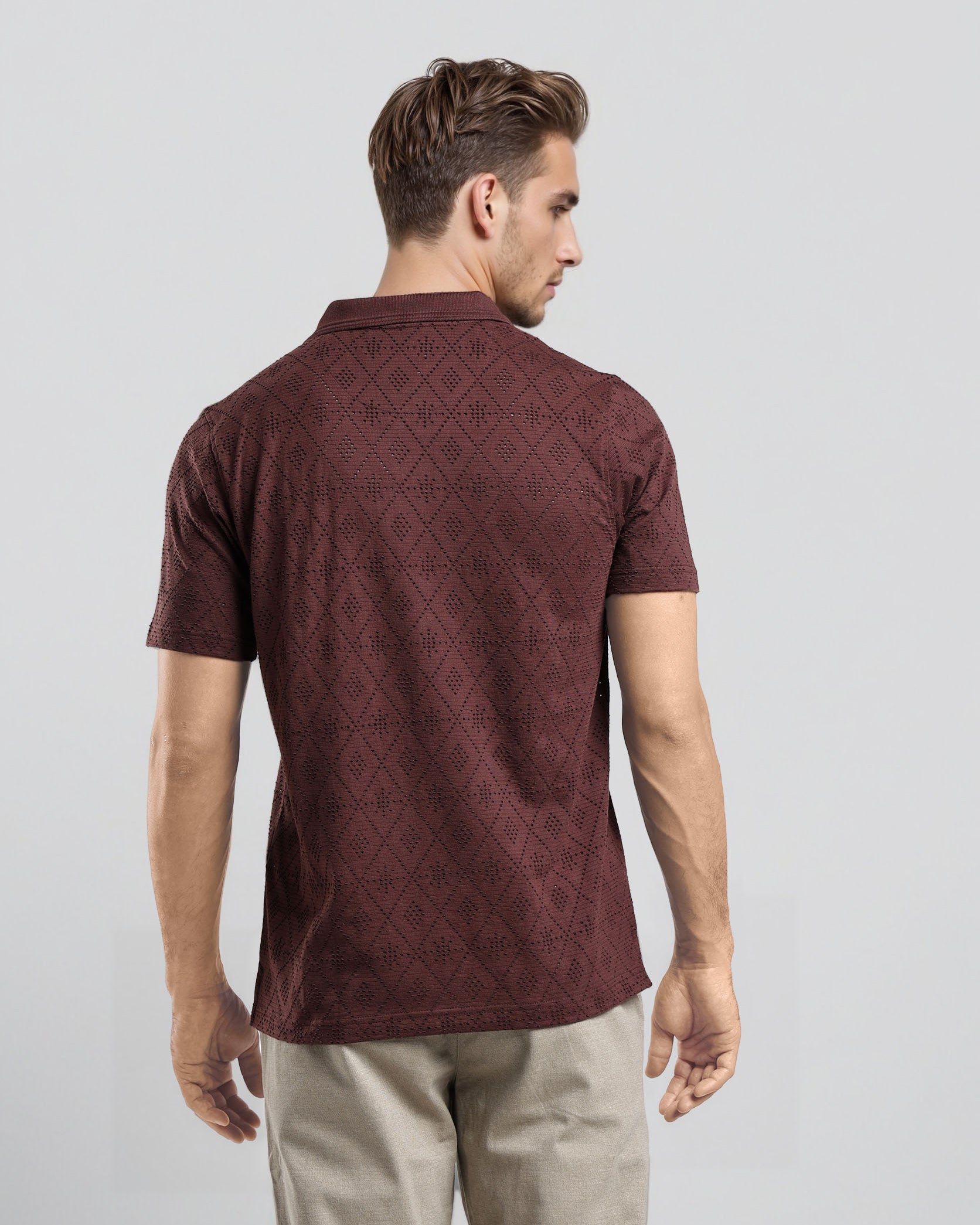 Man wearing a maroon patterned polo shirt on a light gray background