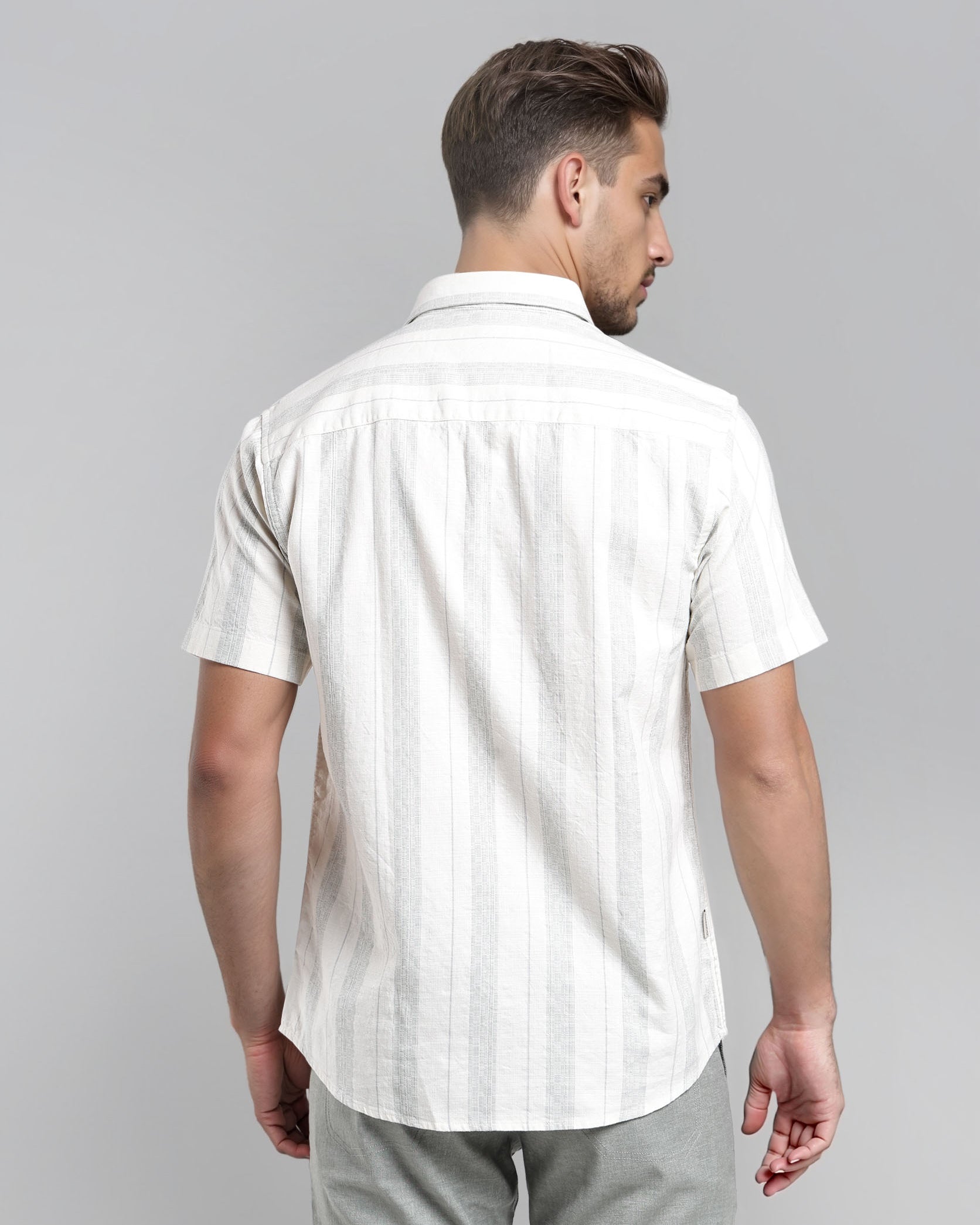 Man wearing a white short-sleeve shirt with subtle pattern on a gray background