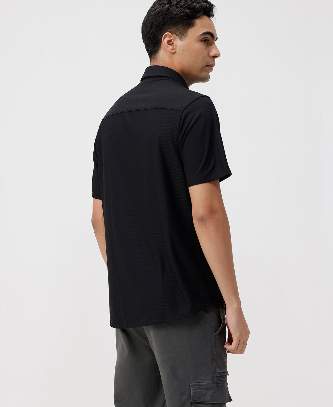 Man wearing a black solid black cotton shirt with casual styling on a gray background