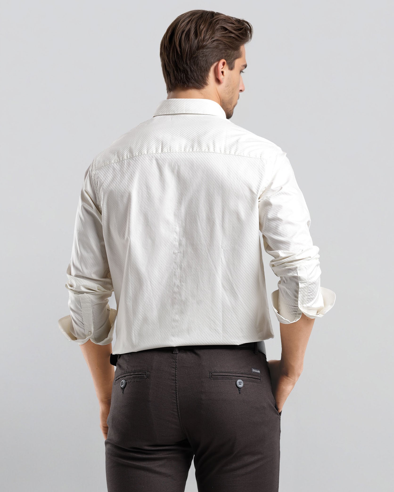 Man wearing a white shirt and dark pants on a light gray background