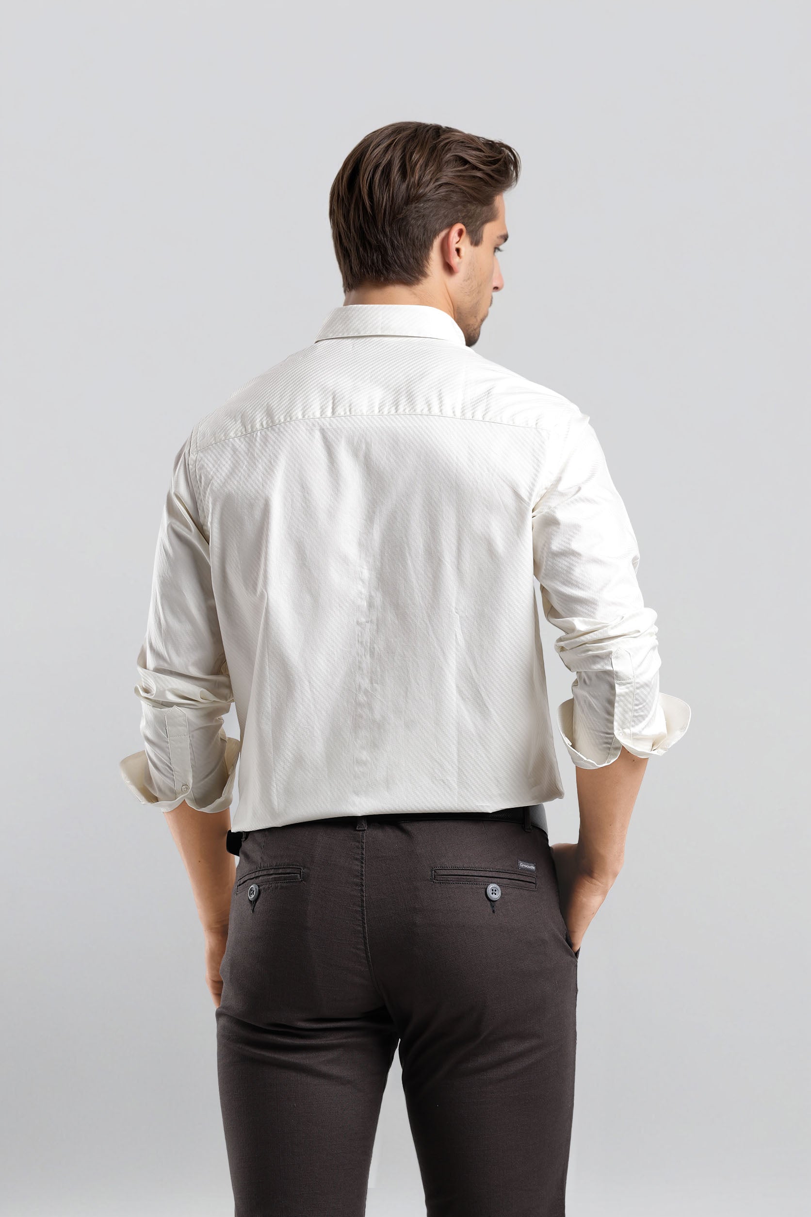 Man wearing a white shirt and dark pants on a light gray background