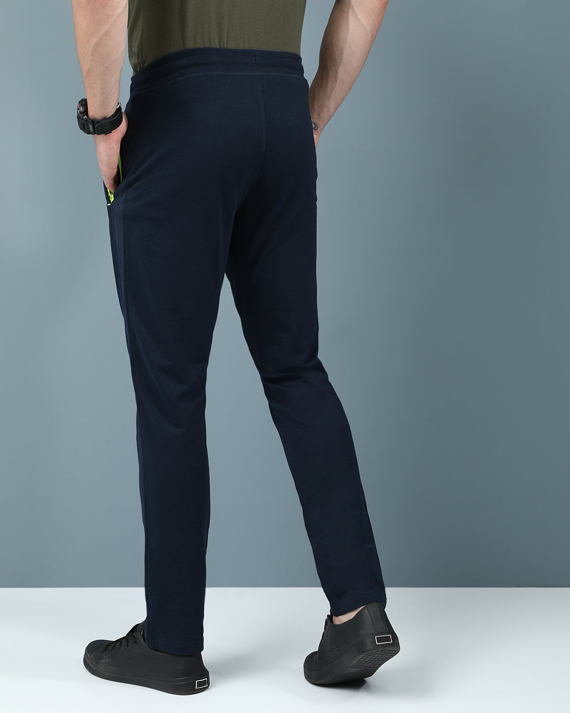 Man wearing a navy slim fit track pants in flexible navy on a light gray background