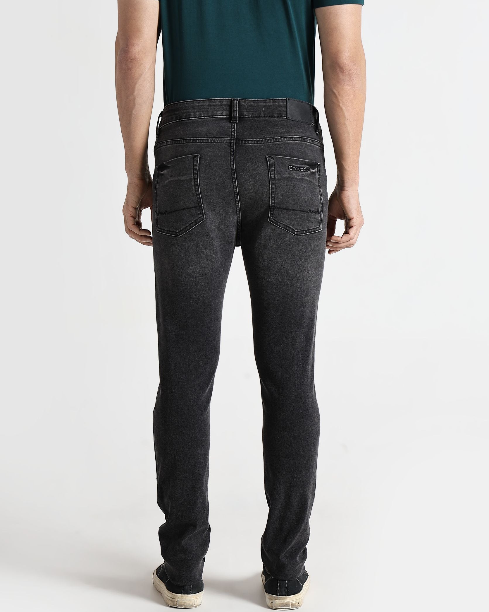 Person wearing black jeans and a green shirt on a white background