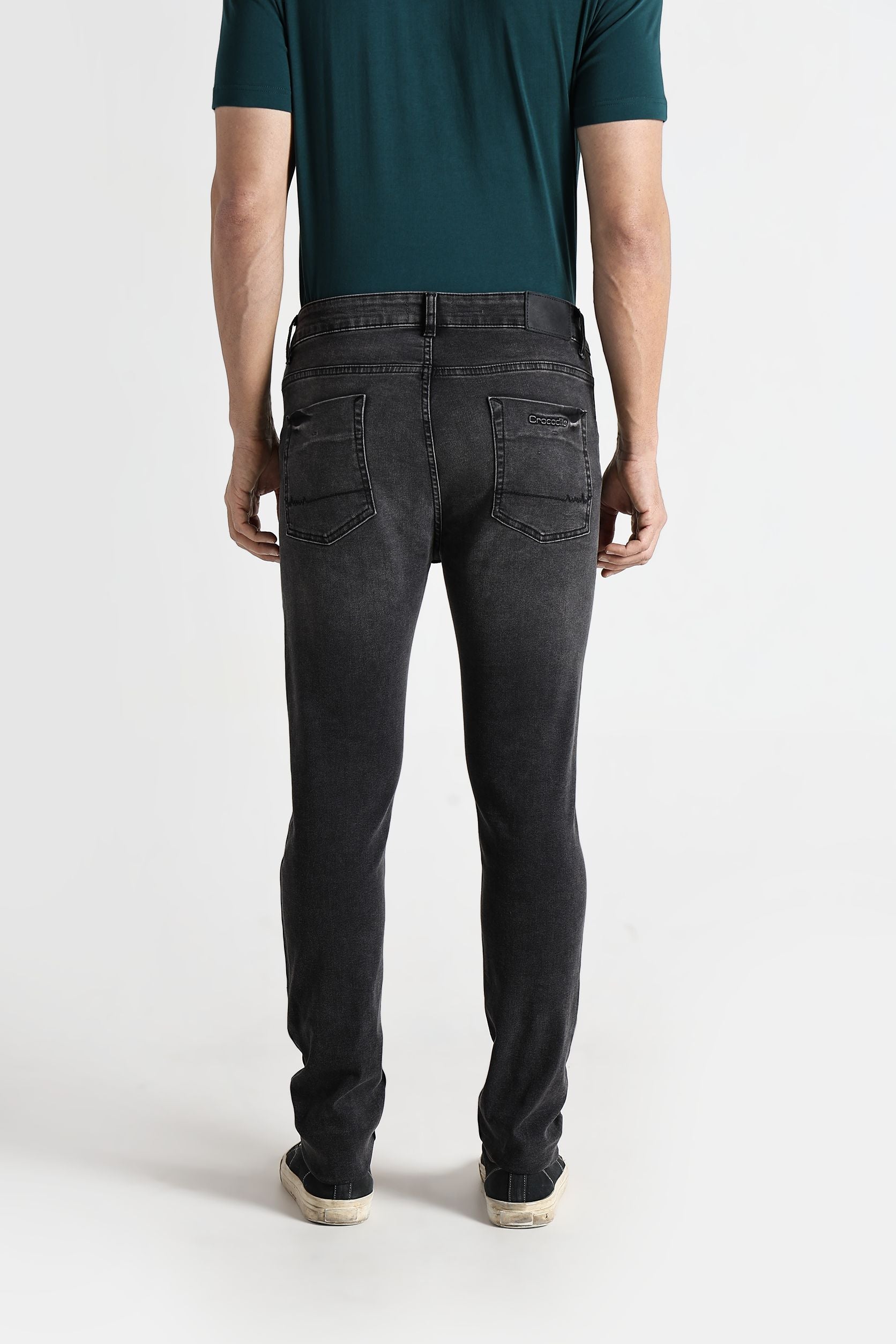 Person wearing black jeans and a green shirt on a white background
