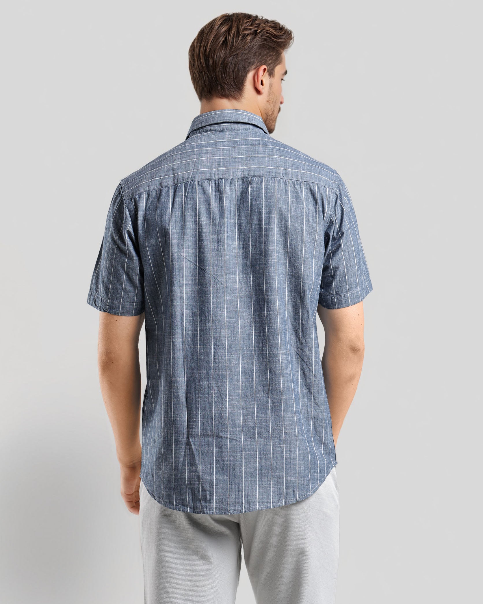 Man wearing a blue checkered shirt against a gray background