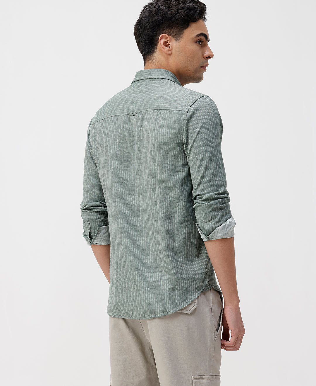 Man wearing a green textured shirt and beige pants on a white background