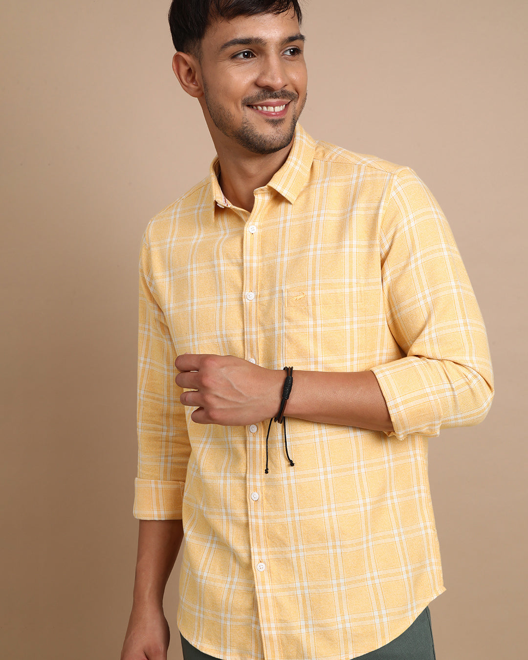 Man wearing a yellow casual yellow checked full sleeve 100% cotton shirt with casual styling on a gray background