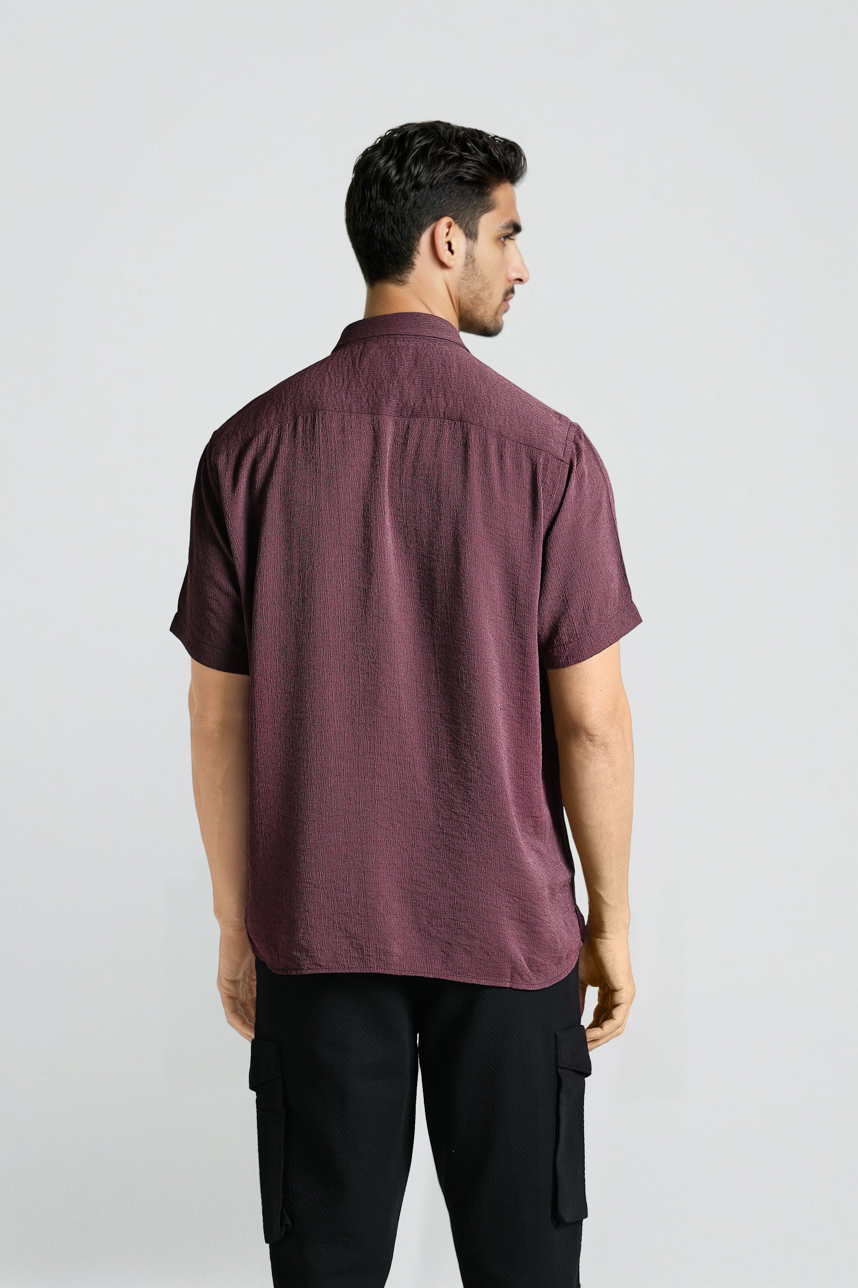 Man wearing a maroon shirt and black pants on a white background