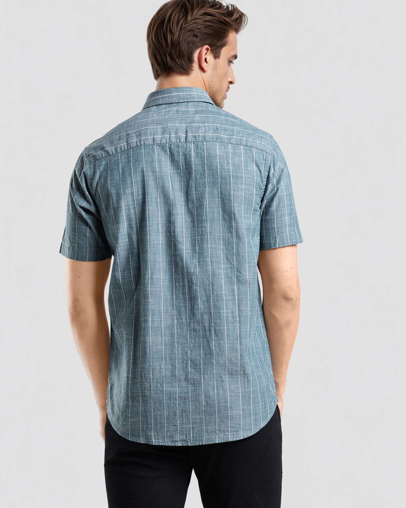 Man wearing a blue checkered shirt on a light gray background