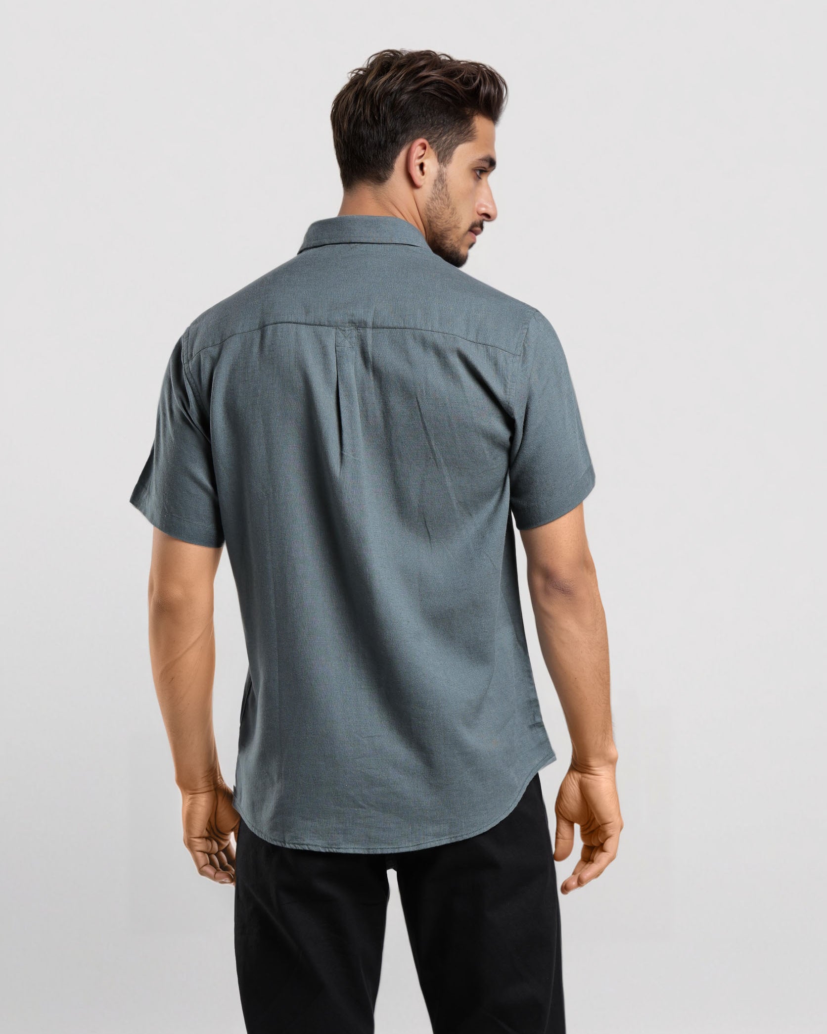 Man wearing a gray short-sleeve shirt and black pants on a white background