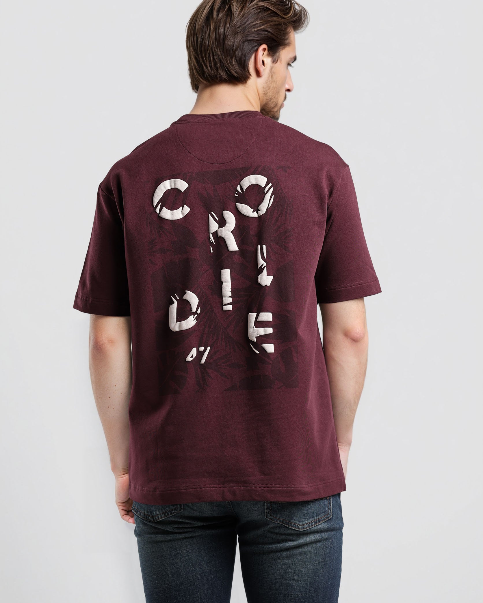 Man wearing a maroon t-shirt with text on the back against a white background