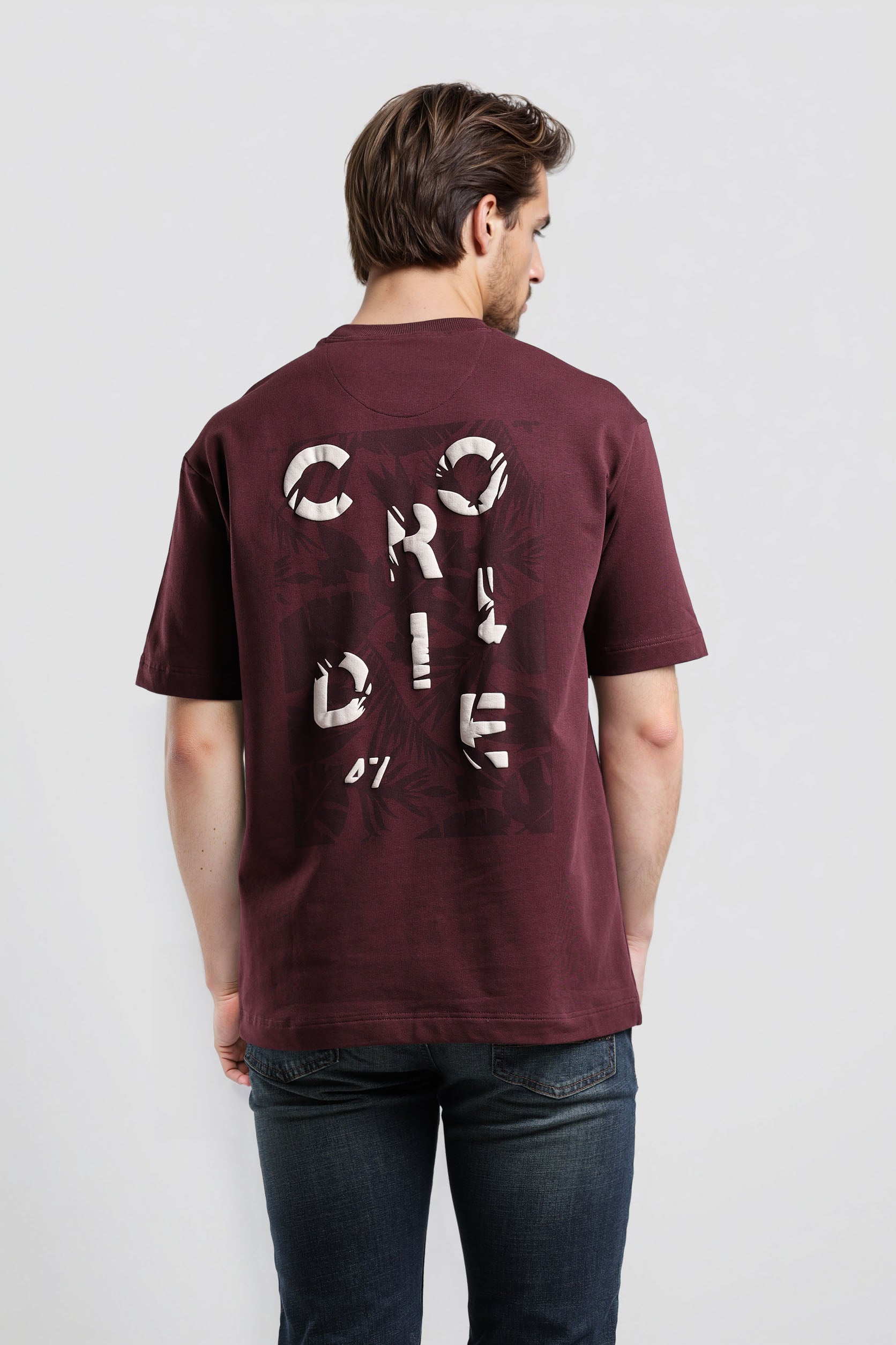 Man wearing a maroon t-shirt with text on the back against a white background