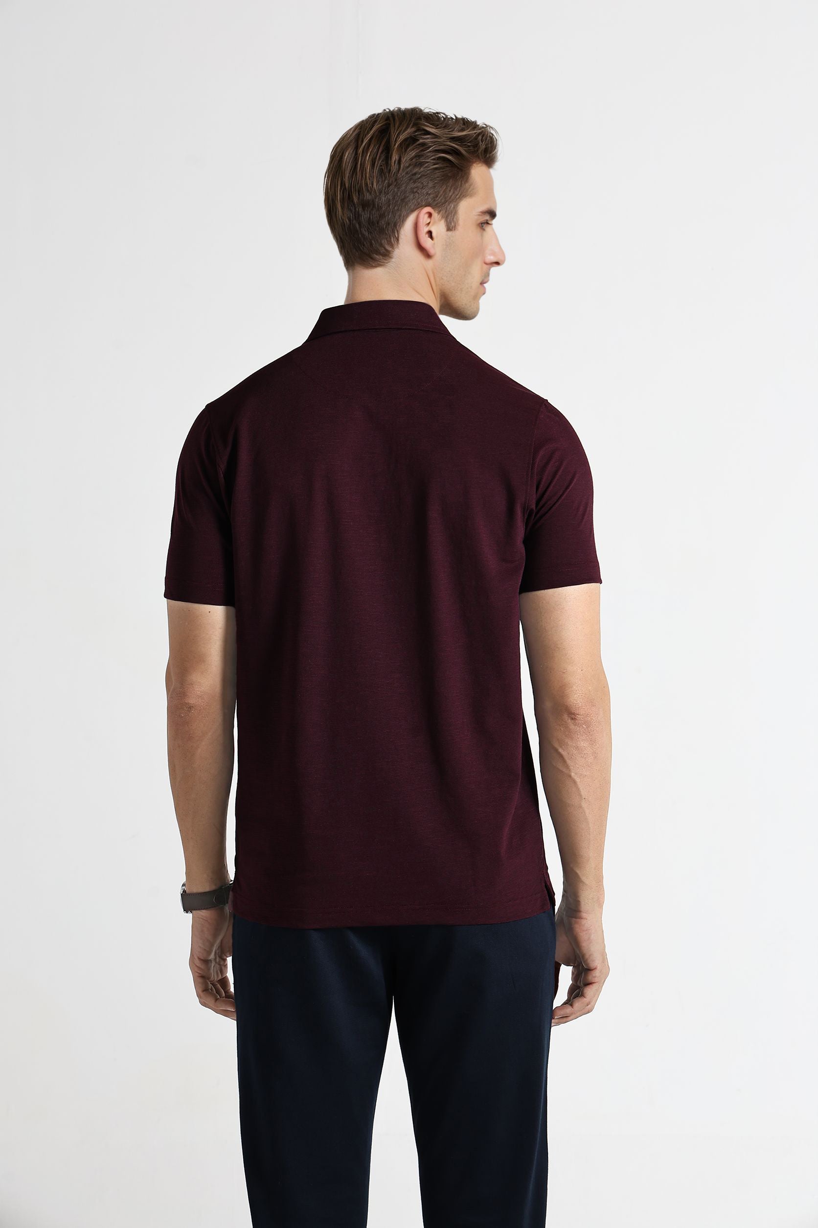 Man wearing a maroon polo shirt on a white background