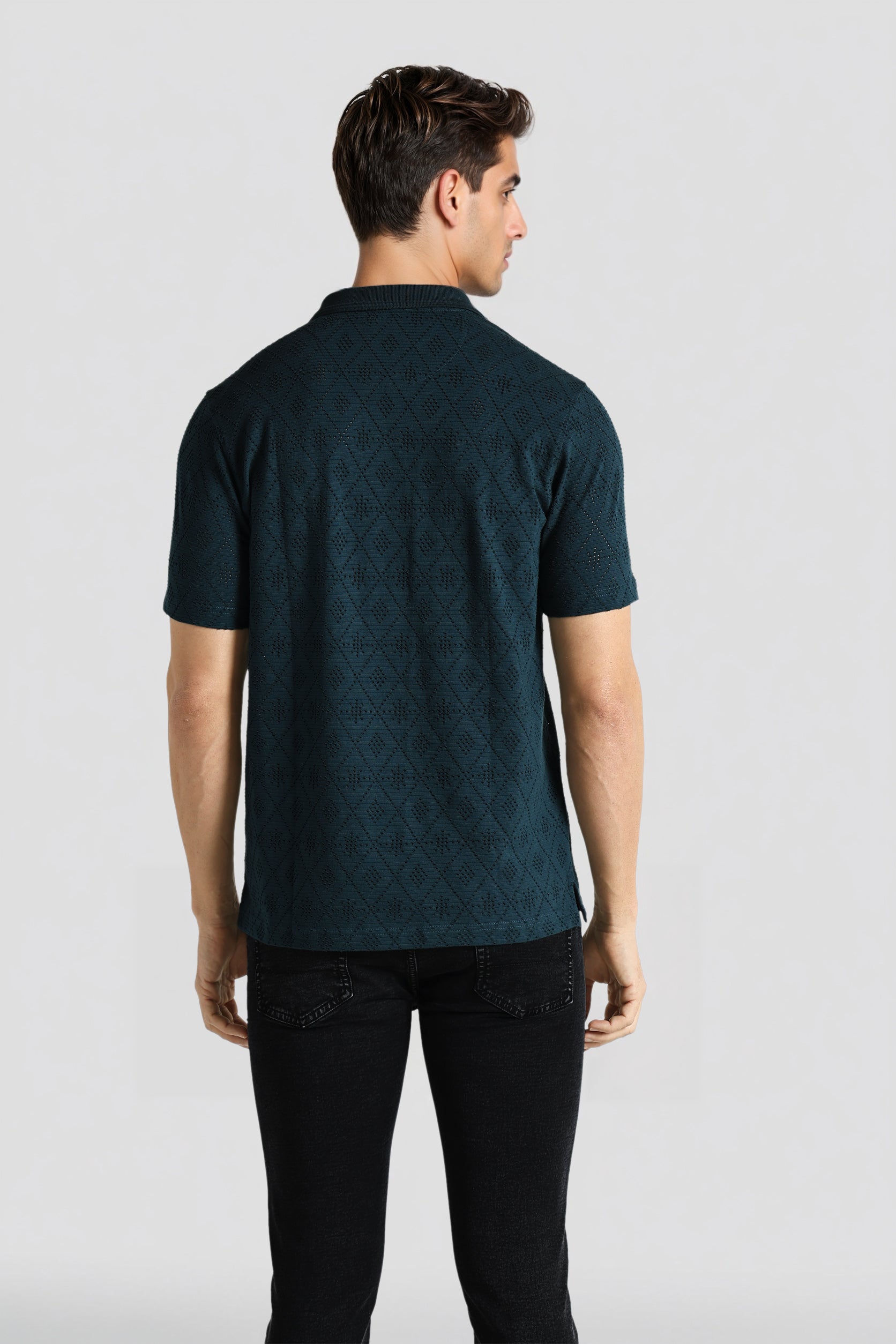 Man wearing a dark green patterned polo shirt on a white background