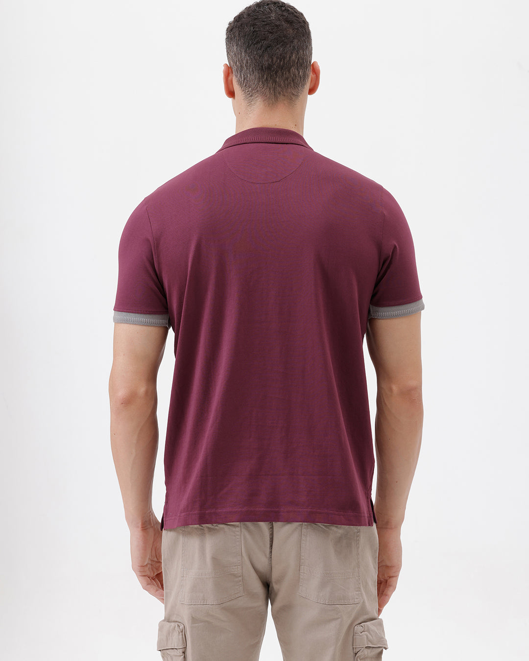 A man wearing a short-sleeve polo shirt in maroon with gray sleeve trim and a half-zip collar, paired with beige cargo pants, against a plain white studio background.