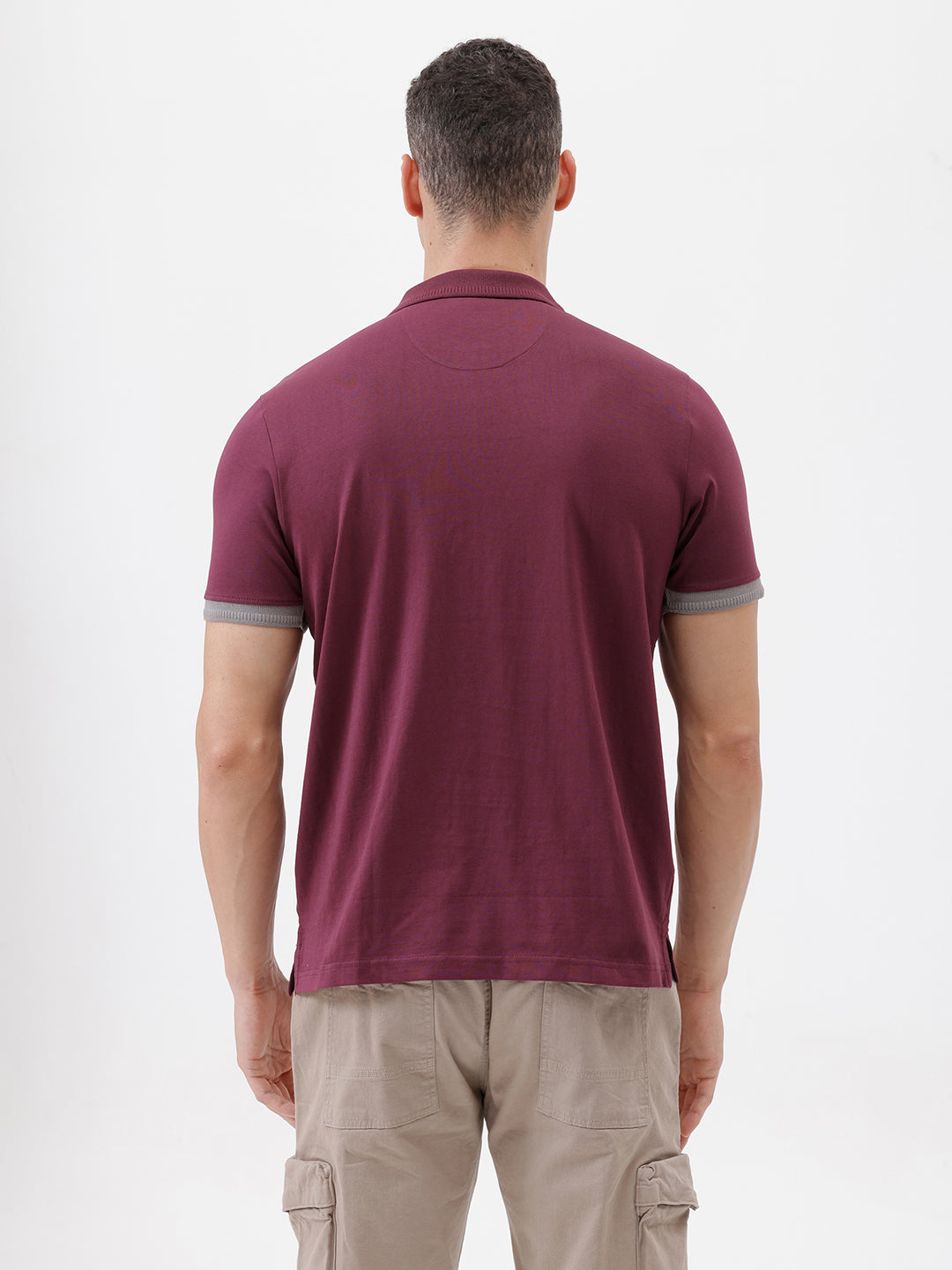 A man wearing a short-sleeve polo shirt in maroon with gray sleeve trim and a half-zip collar, paired with beige cargo pants, against a plain white studio background.
