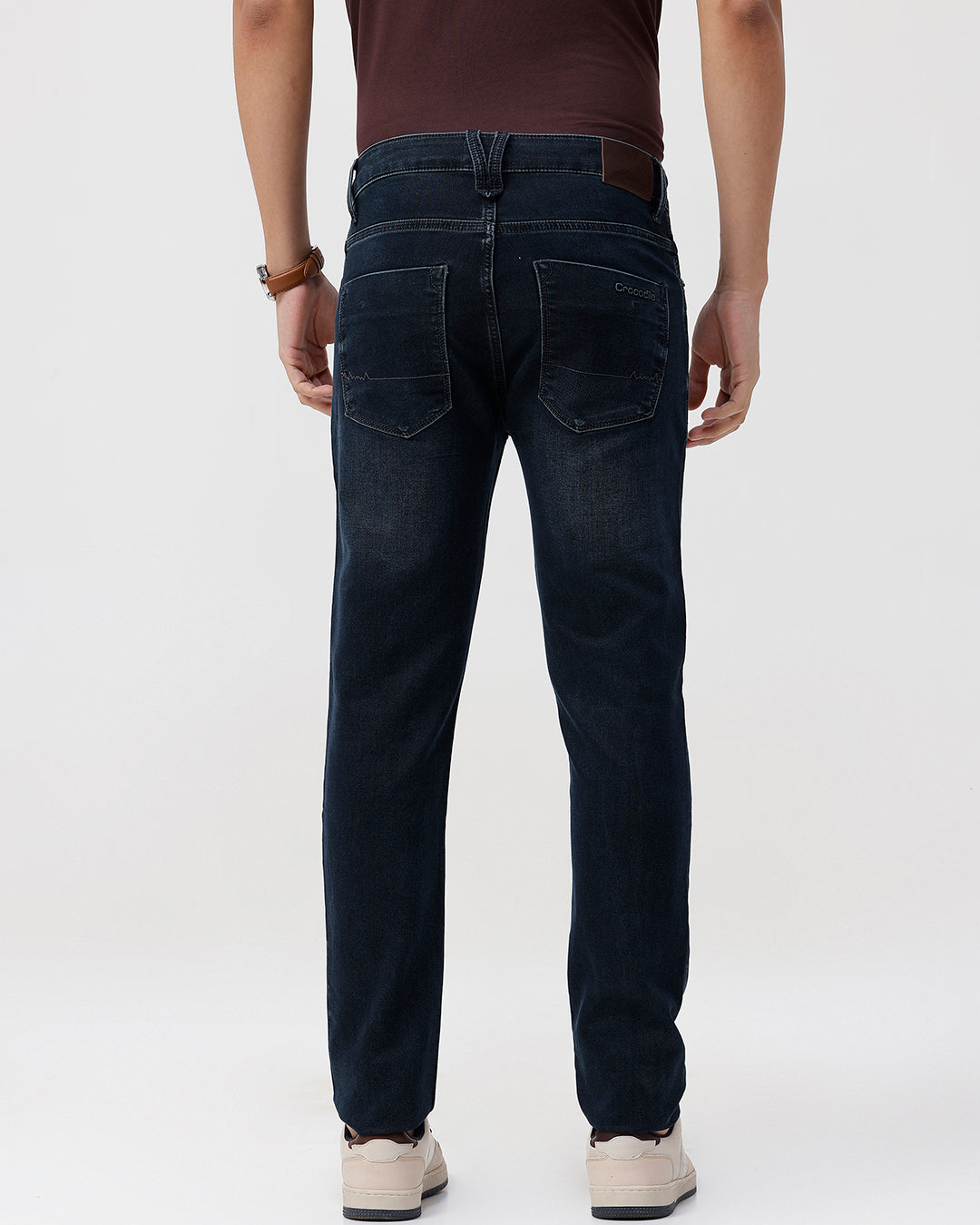 Person wearing dark blue jeans on a white background