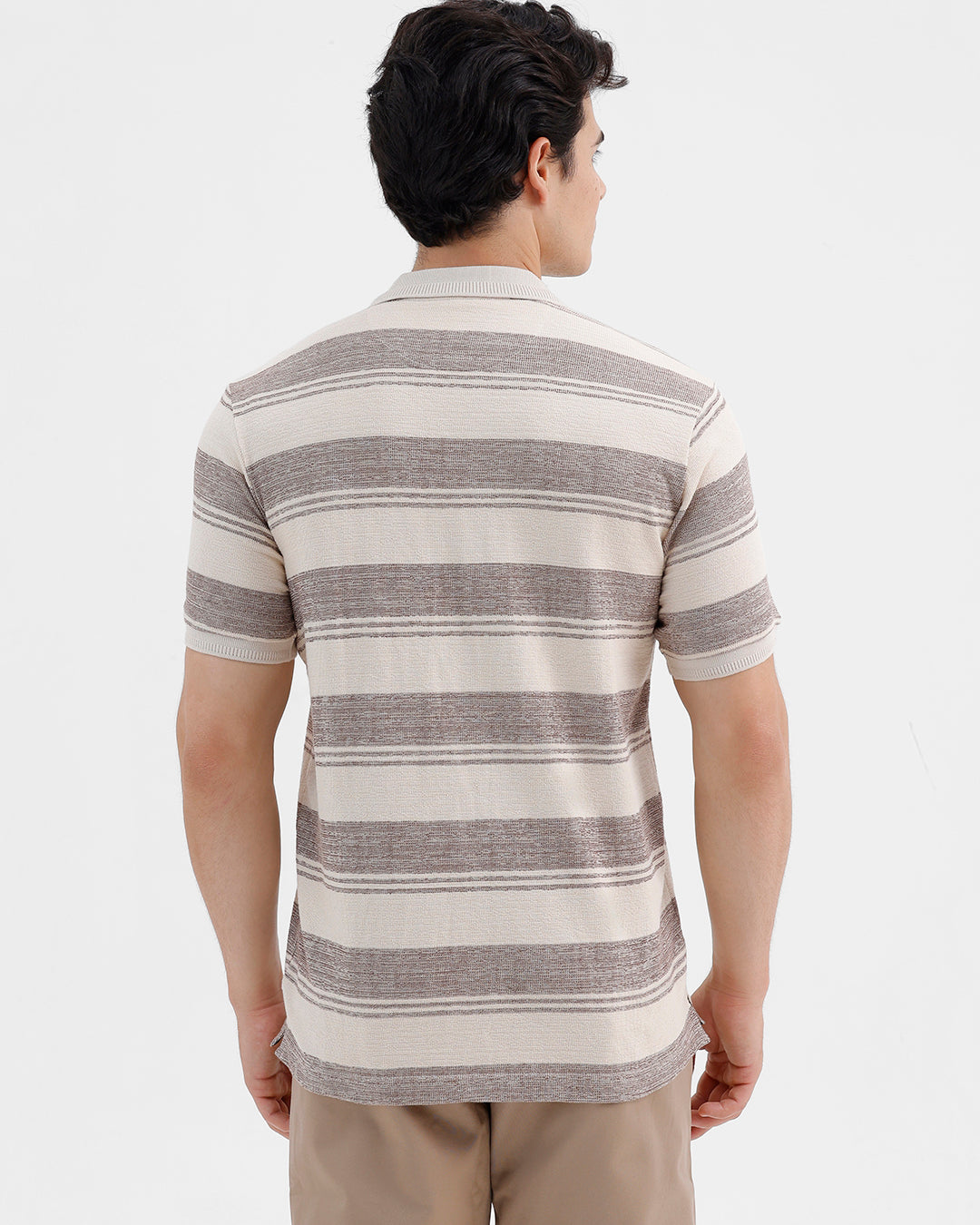 Man wearing a retro classic checked all over printed polo t shirt with casual styling on a gray background