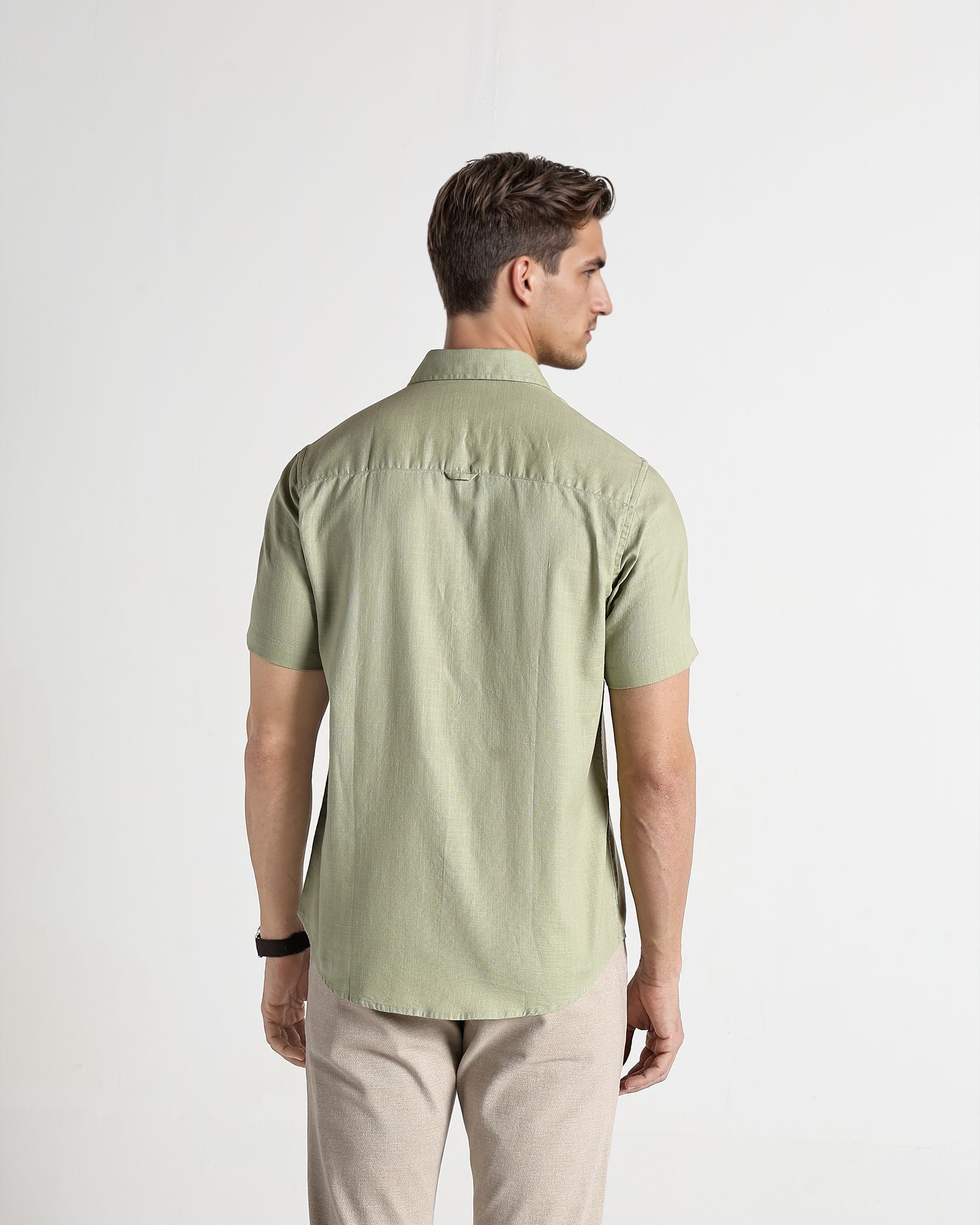 Man wearing a light green shirt and beige pants on a white background