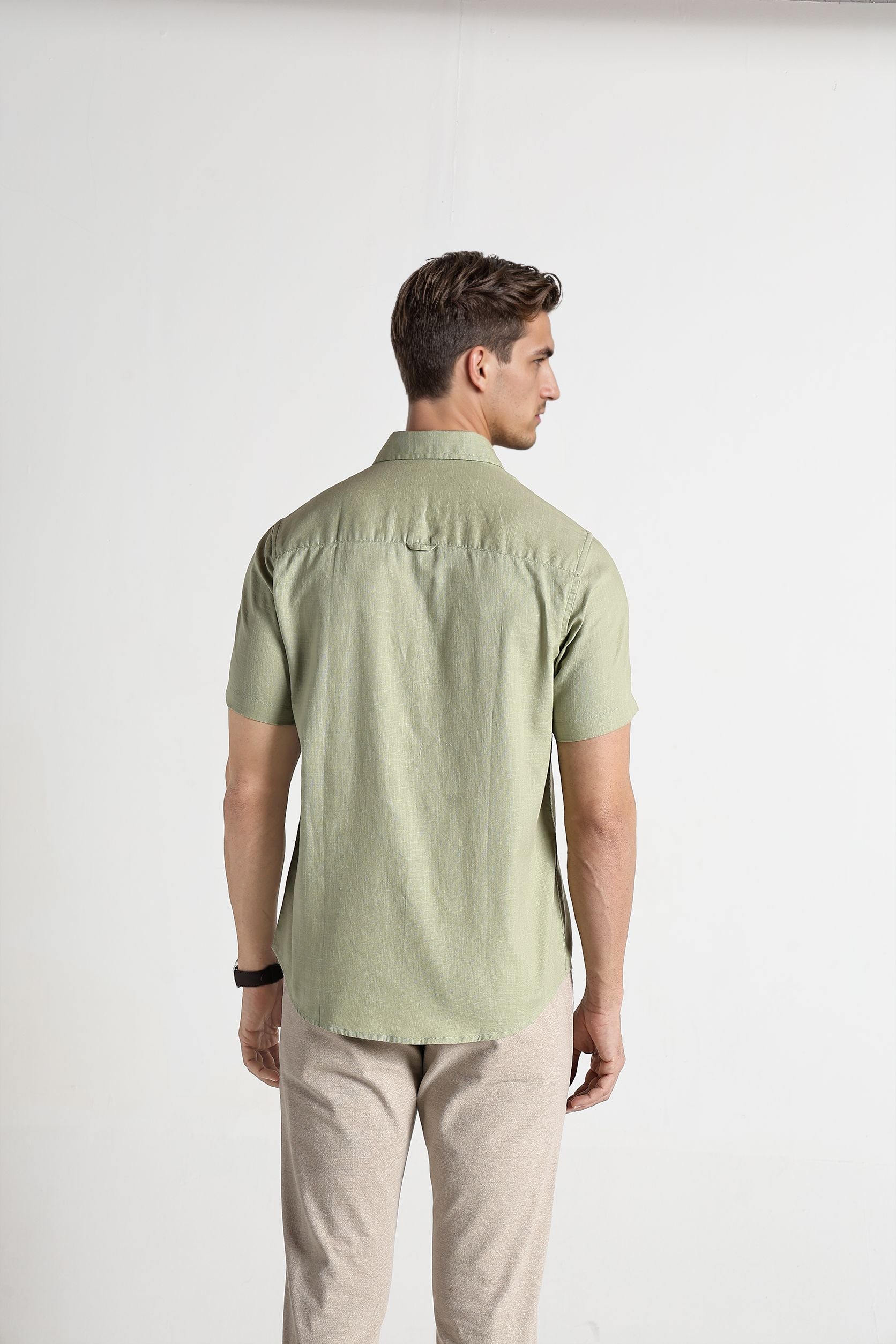 Man wearing a light green shirt and beige pants on a white background