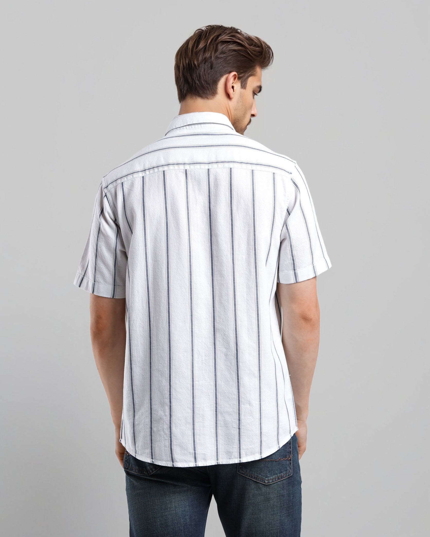 Man wearing a white short-sleeve shirt with black stripes on a gray background