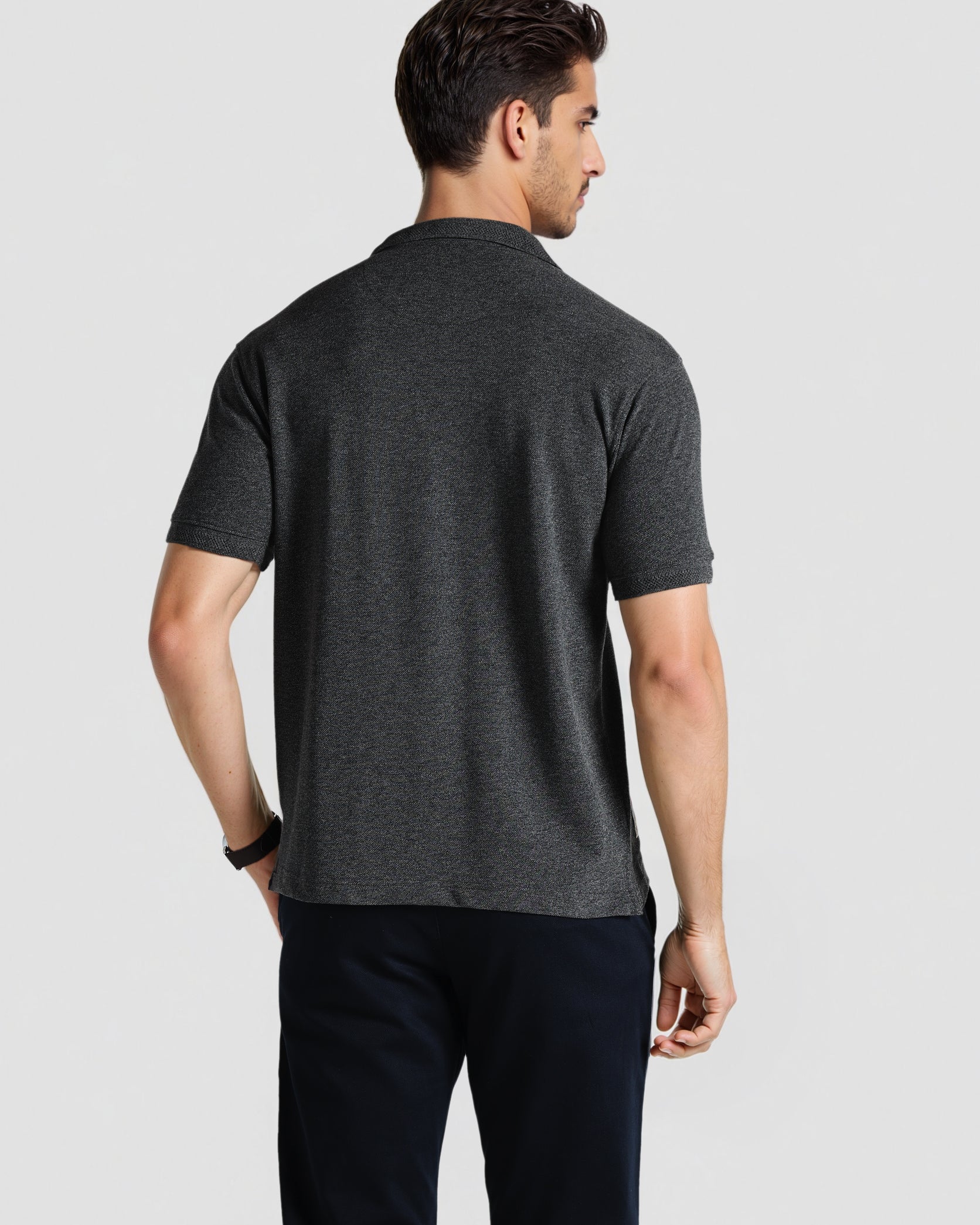 Man wearing a dark gray t-shirt and black pants on a light gray background