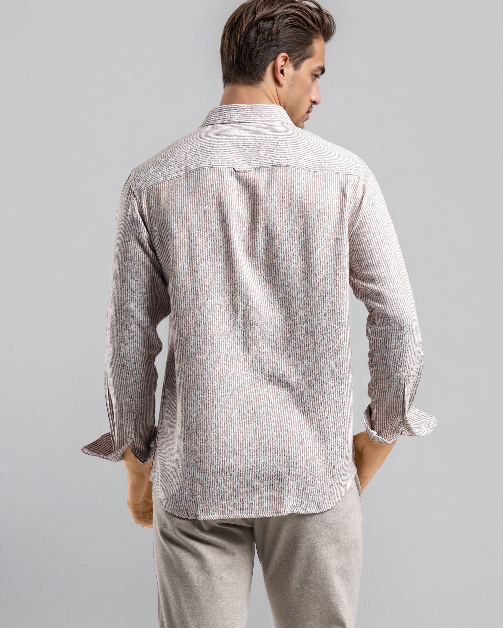 Man wearing a light gray striped shirt and pants on a plain background