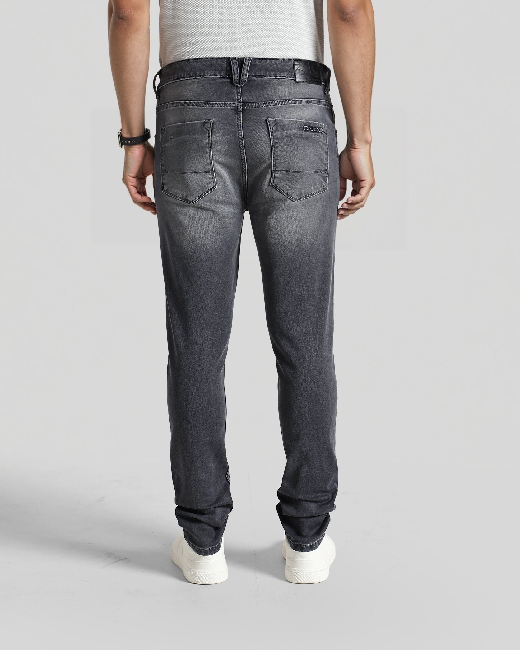 Person wearing black jeans on a plain background