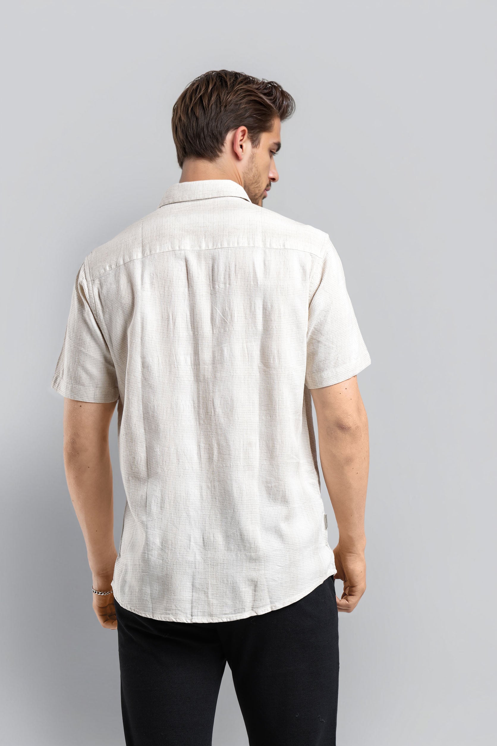 Man wearing a light-colored short-sleeve shirt on a gray background