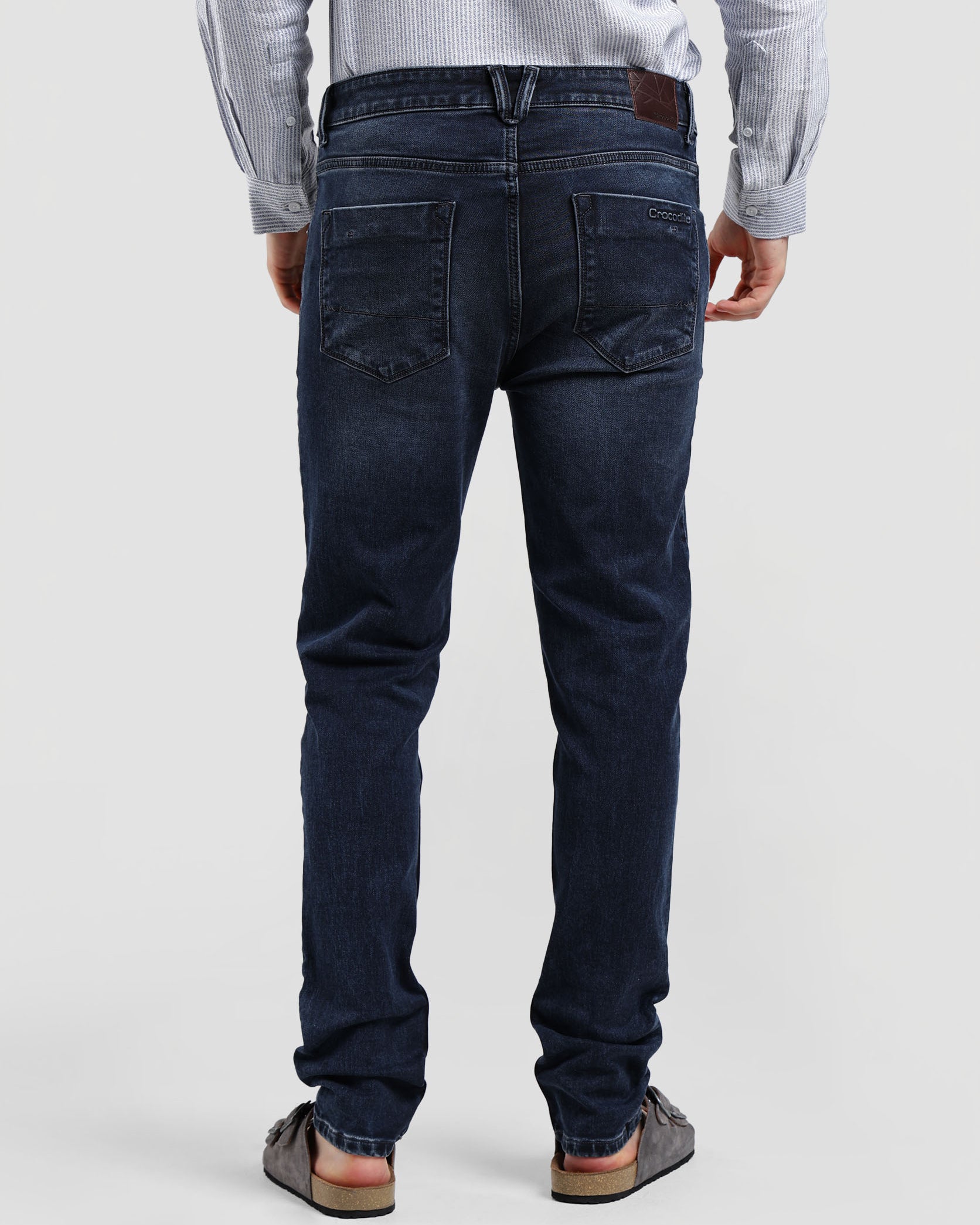 Person wearing dark blue jeans on a plain background