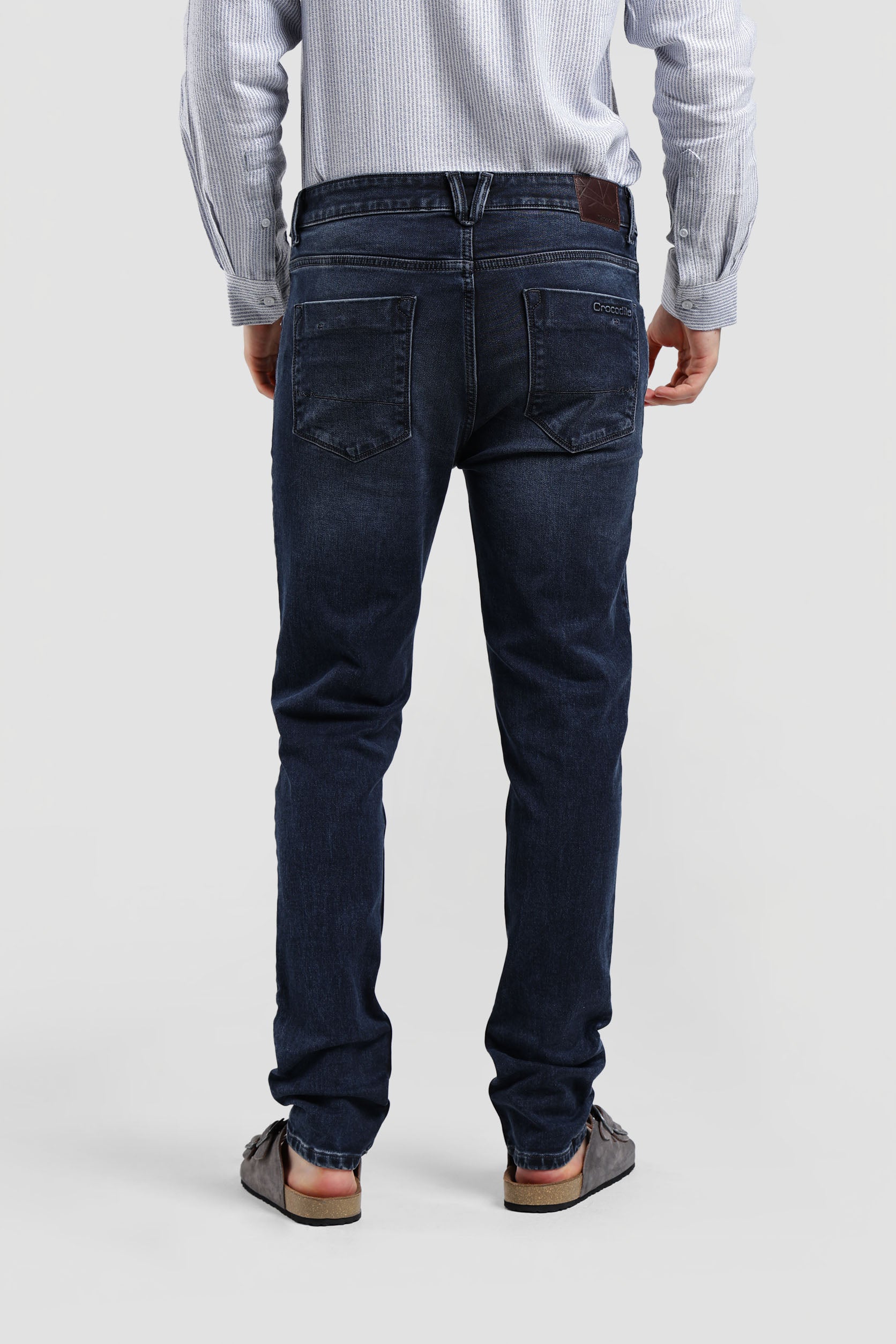 Person wearing dark blue jeans on a plain background