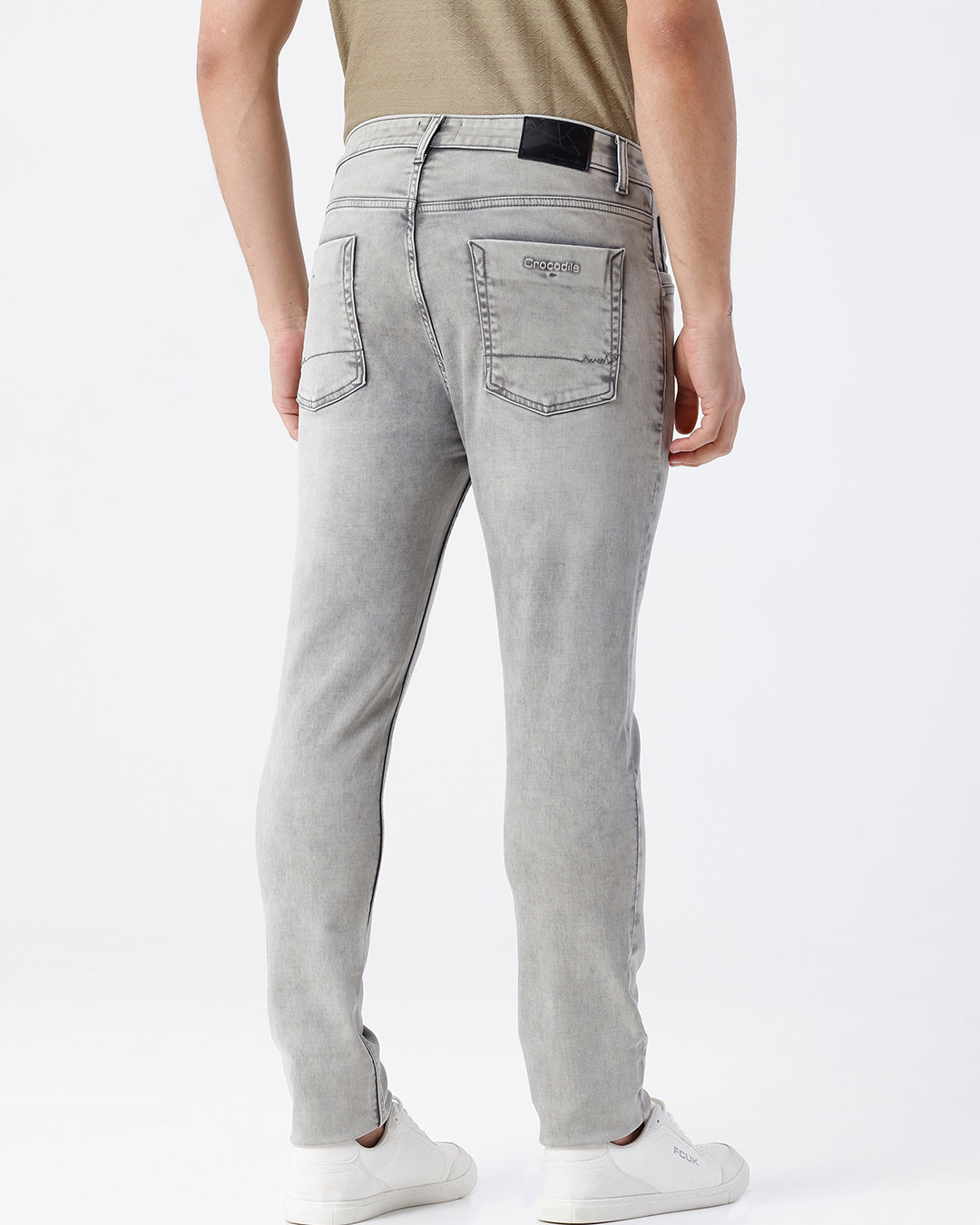 Man wearing a grey light grey knit slim fit jeans on a light gray background