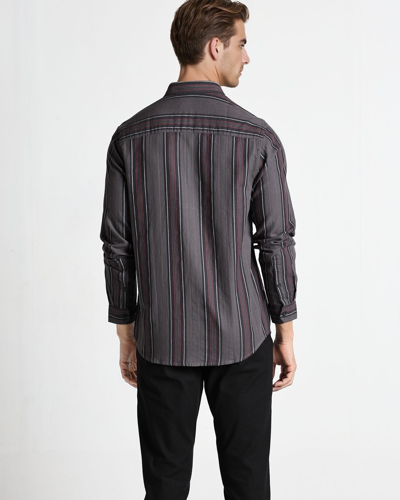 Man wearing a striped shirt and black pants on a white background