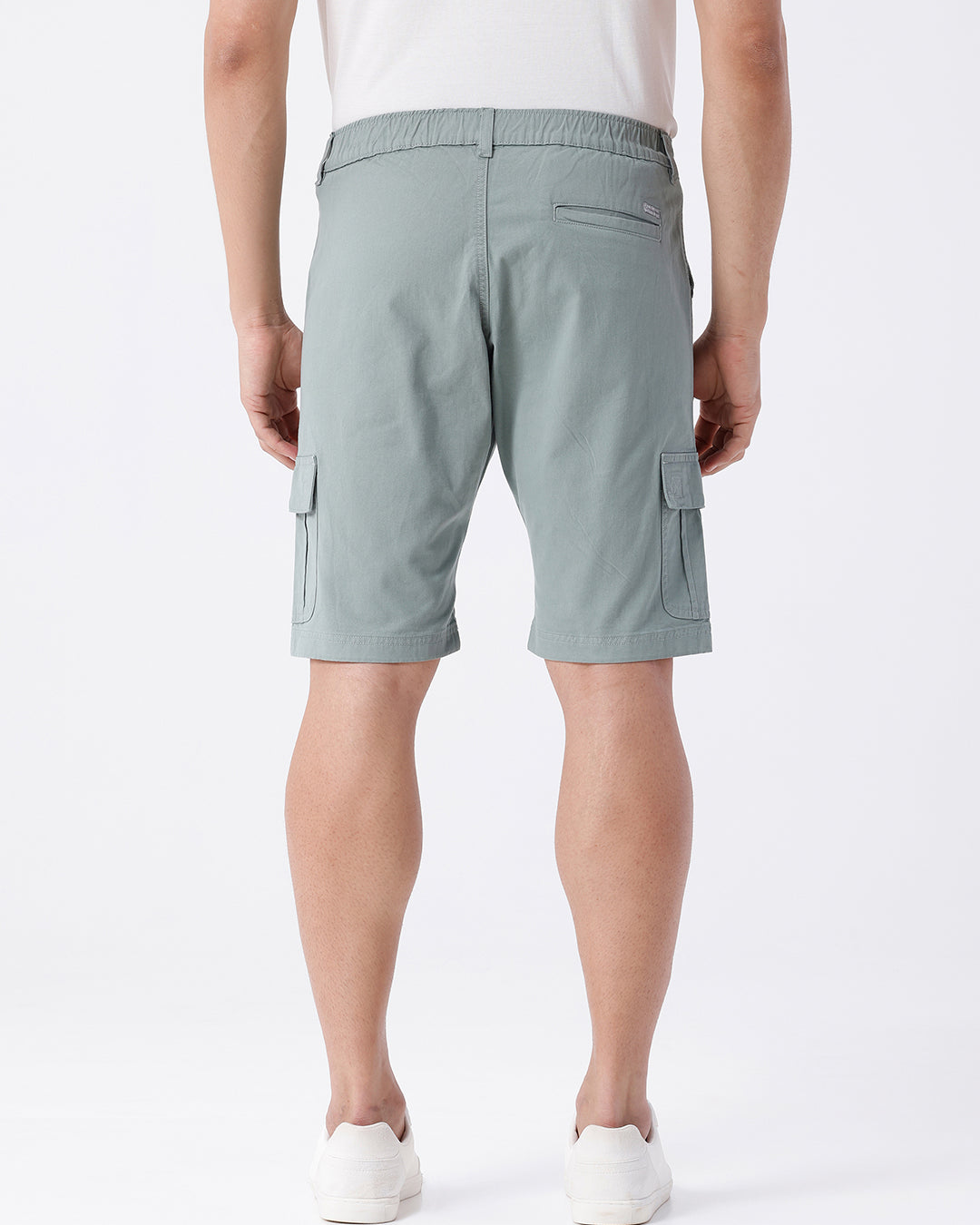 Man wearing a olive garment dyed cargo shorts in olive on a light gray background