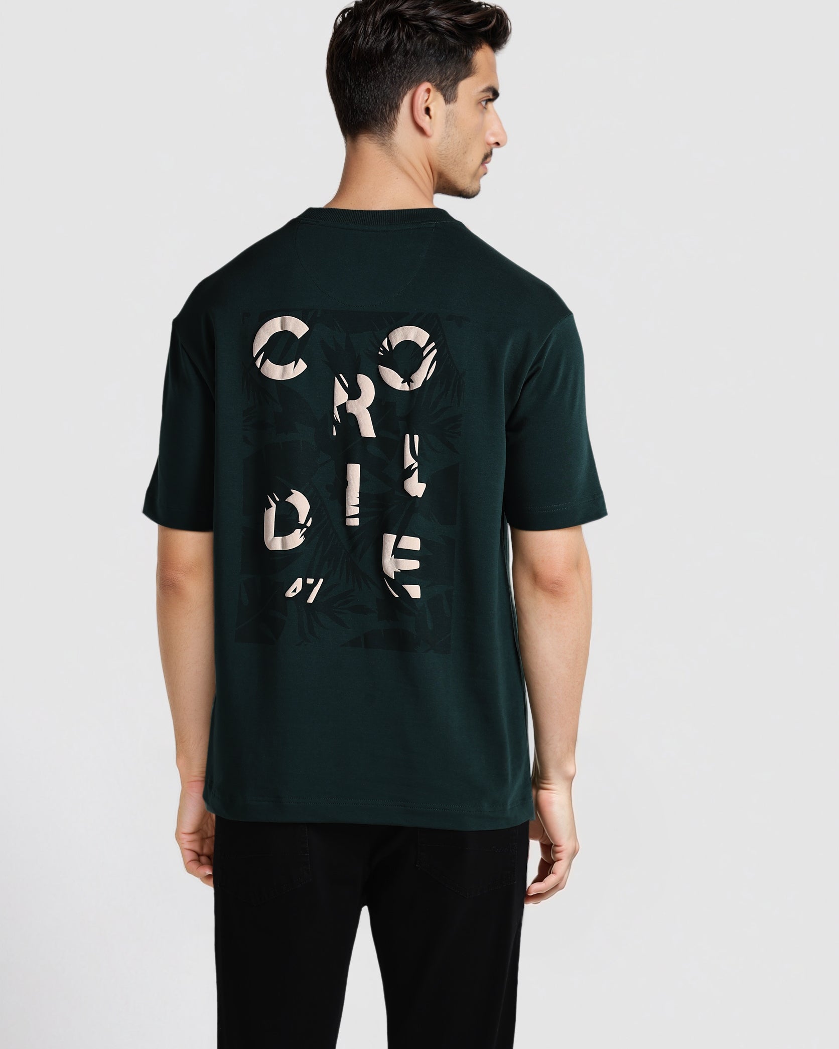 Man wearing a dark green t-shirt with text on the back against a white background