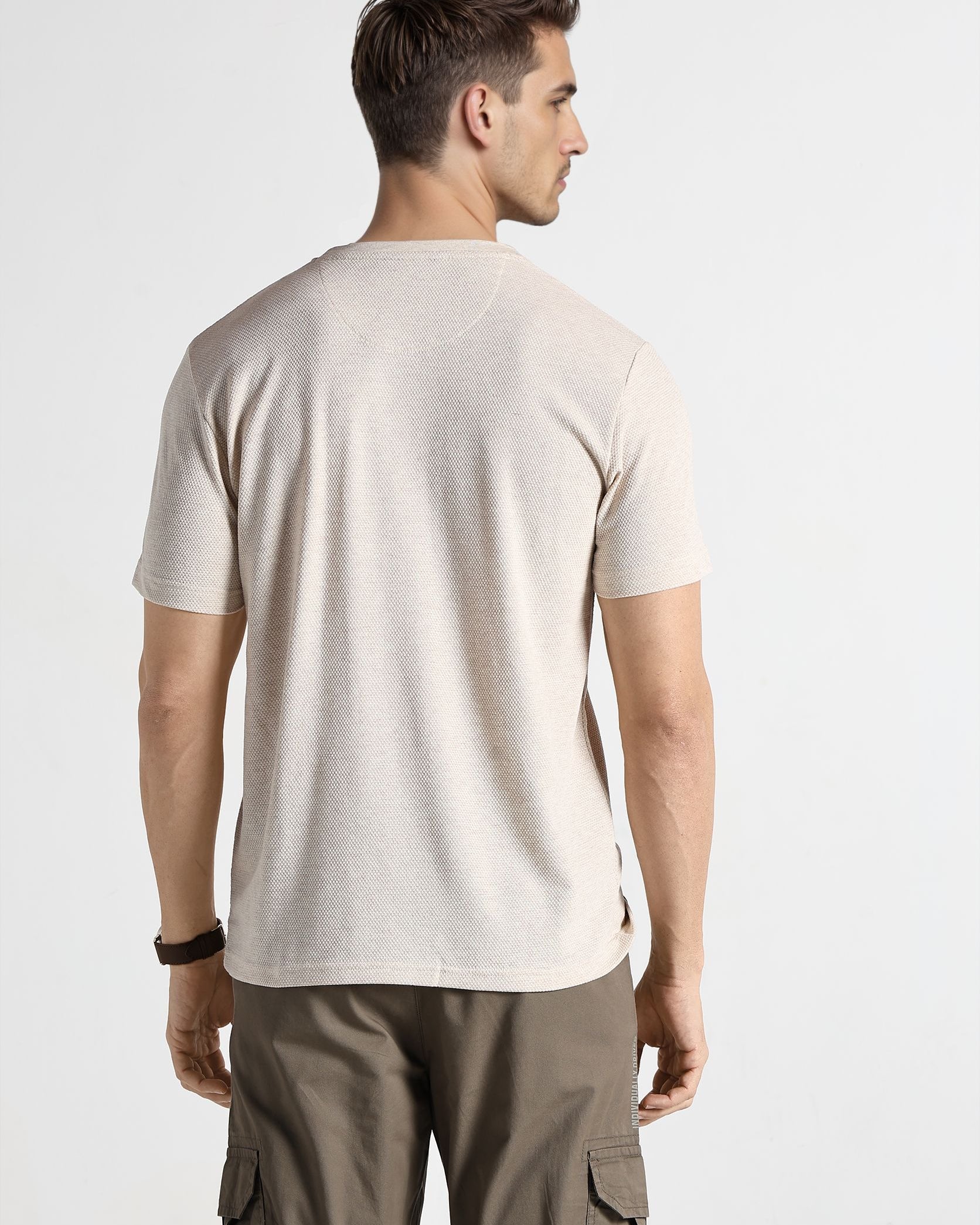 Man wearing a beige t-shirt and cargo pants on a white background