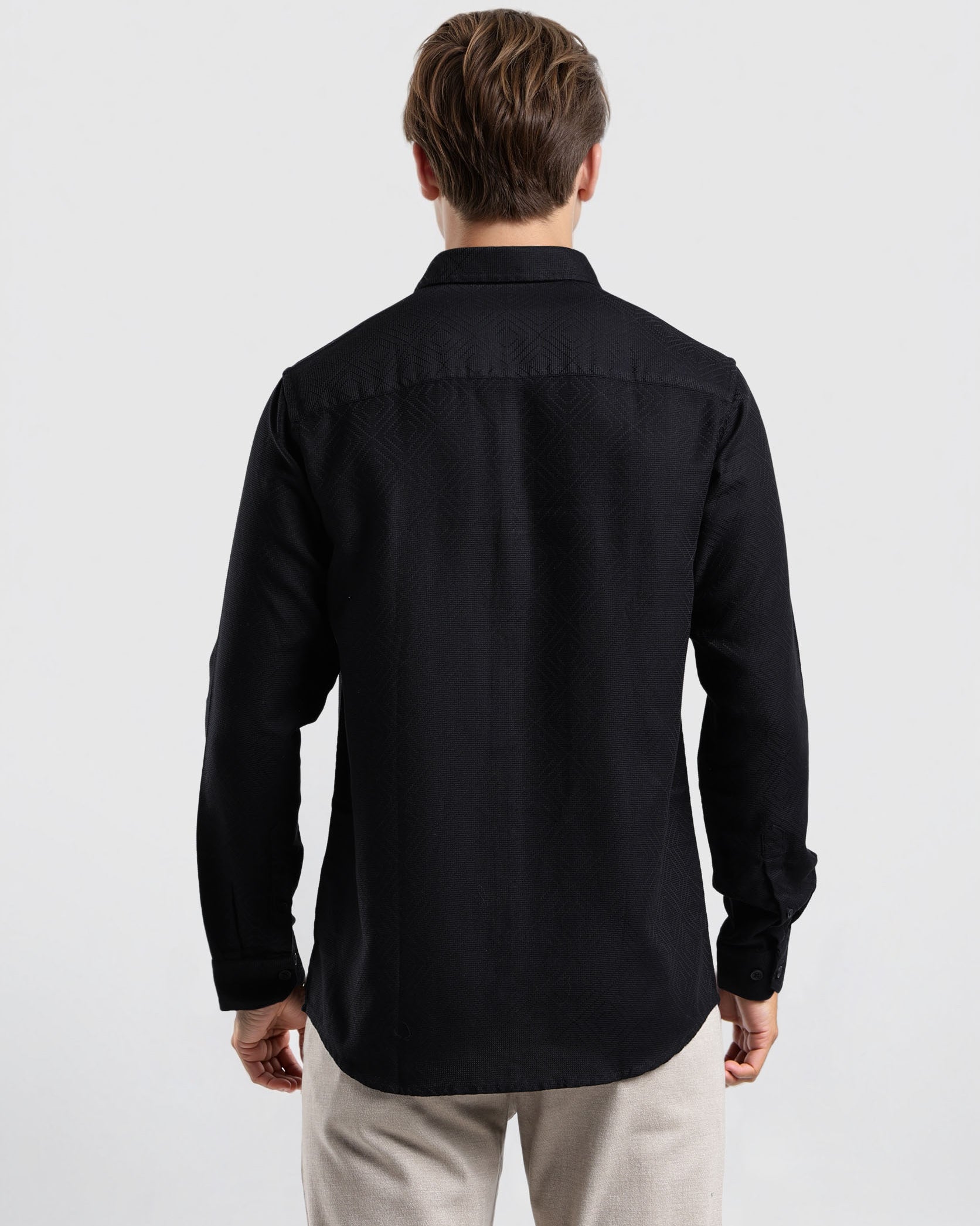 Man wearing a black shirt and light-colored pants on a white background