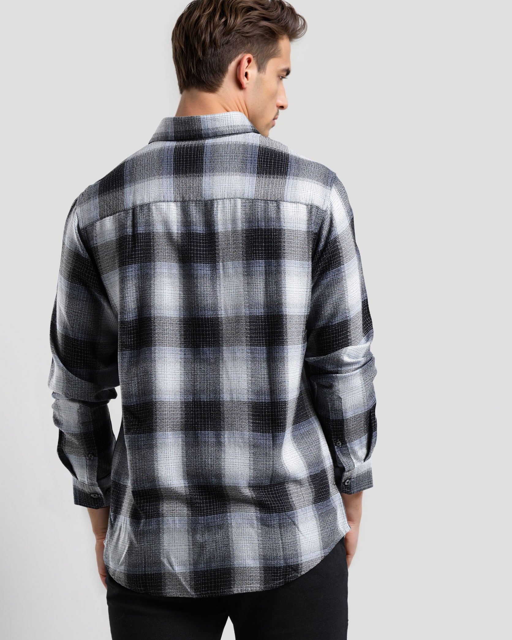Man wearing a black and gray plaid shirt on a light gray background