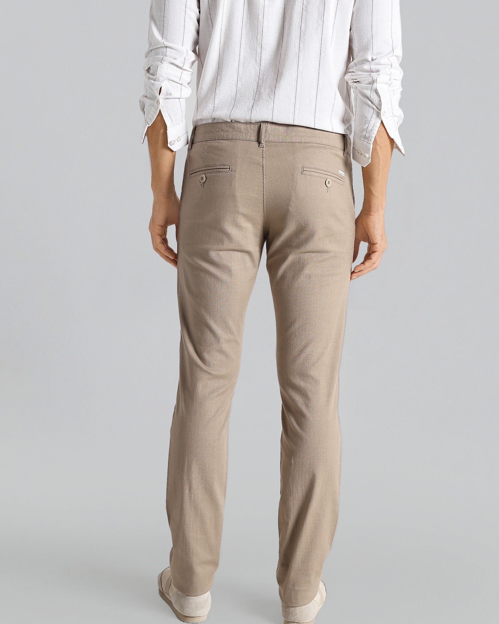 Person wearing beige pants and a white shirt on a gray background