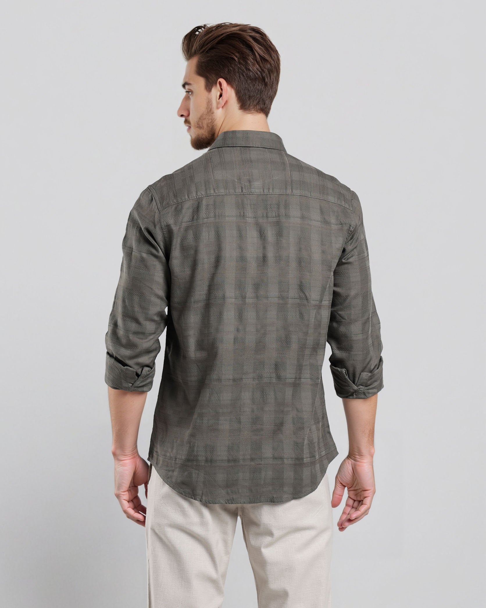 Man wearing a gray checkered shirt and white pants on a light gray background