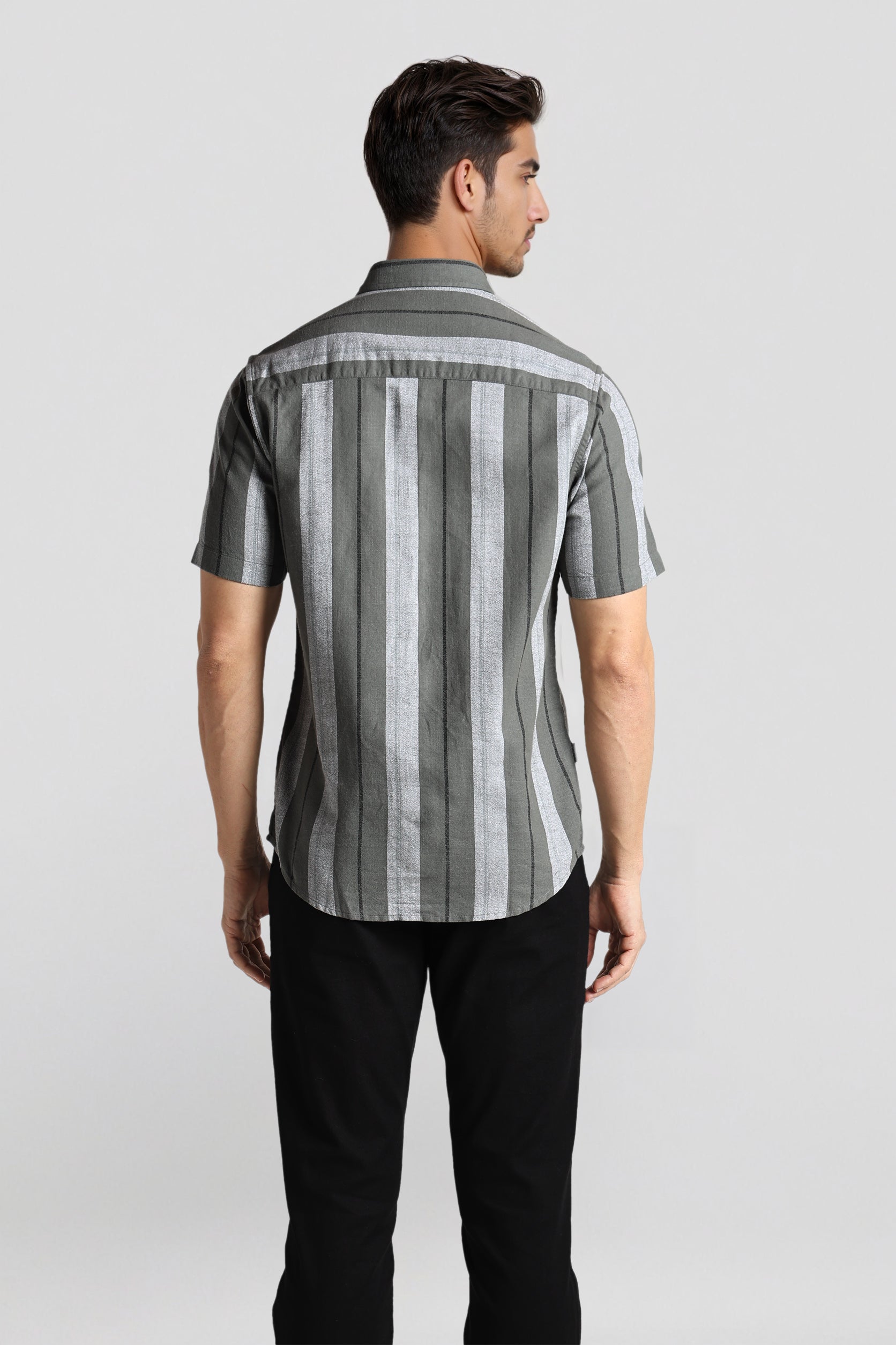 Man wearing a striped shirt and black pants on a light gray background