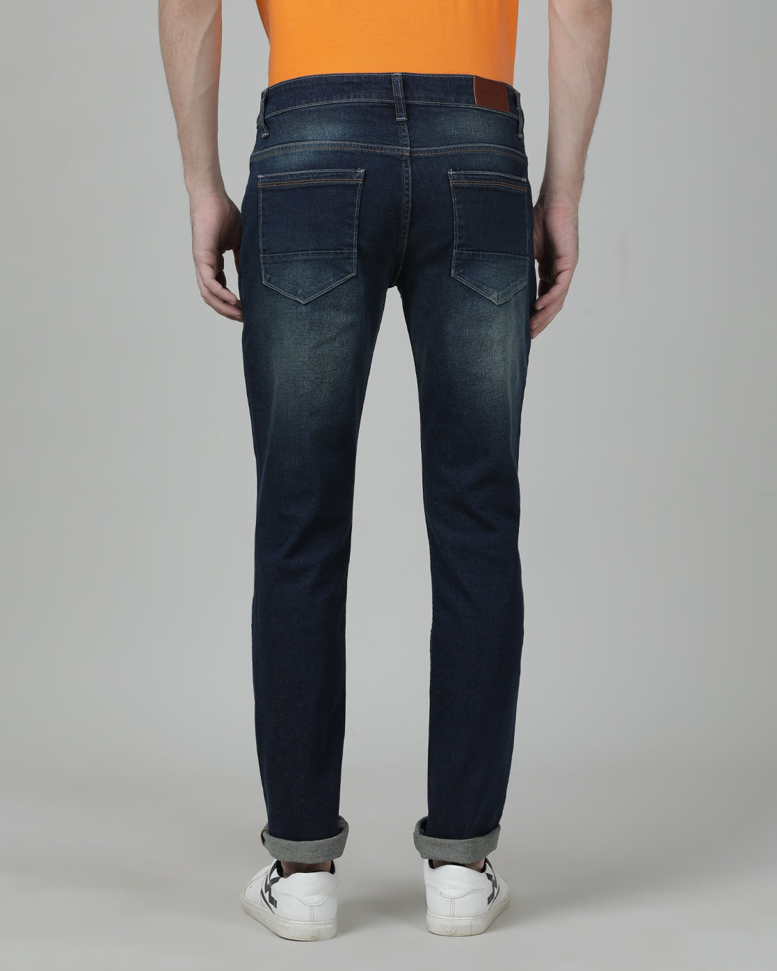 Man wearing a blue medium blue solid mid rise slim fit jean on a light gray background