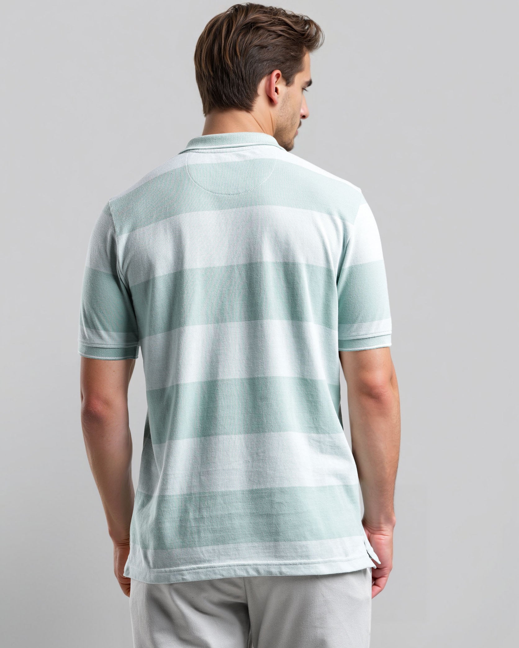 Man wearing a light green and white striped polo shirt on a gray background