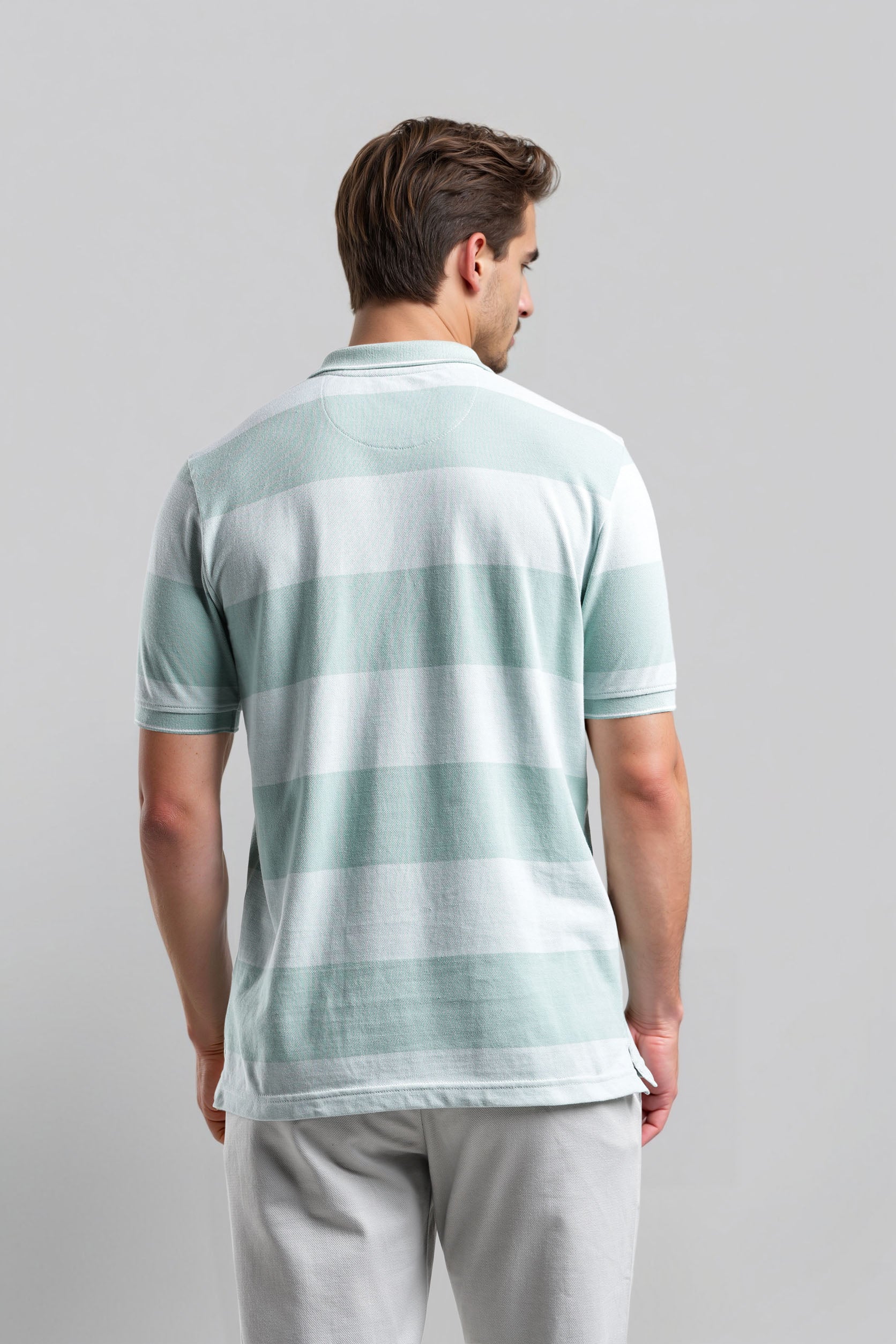 Man wearing a light green and white striped polo shirt on a gray background